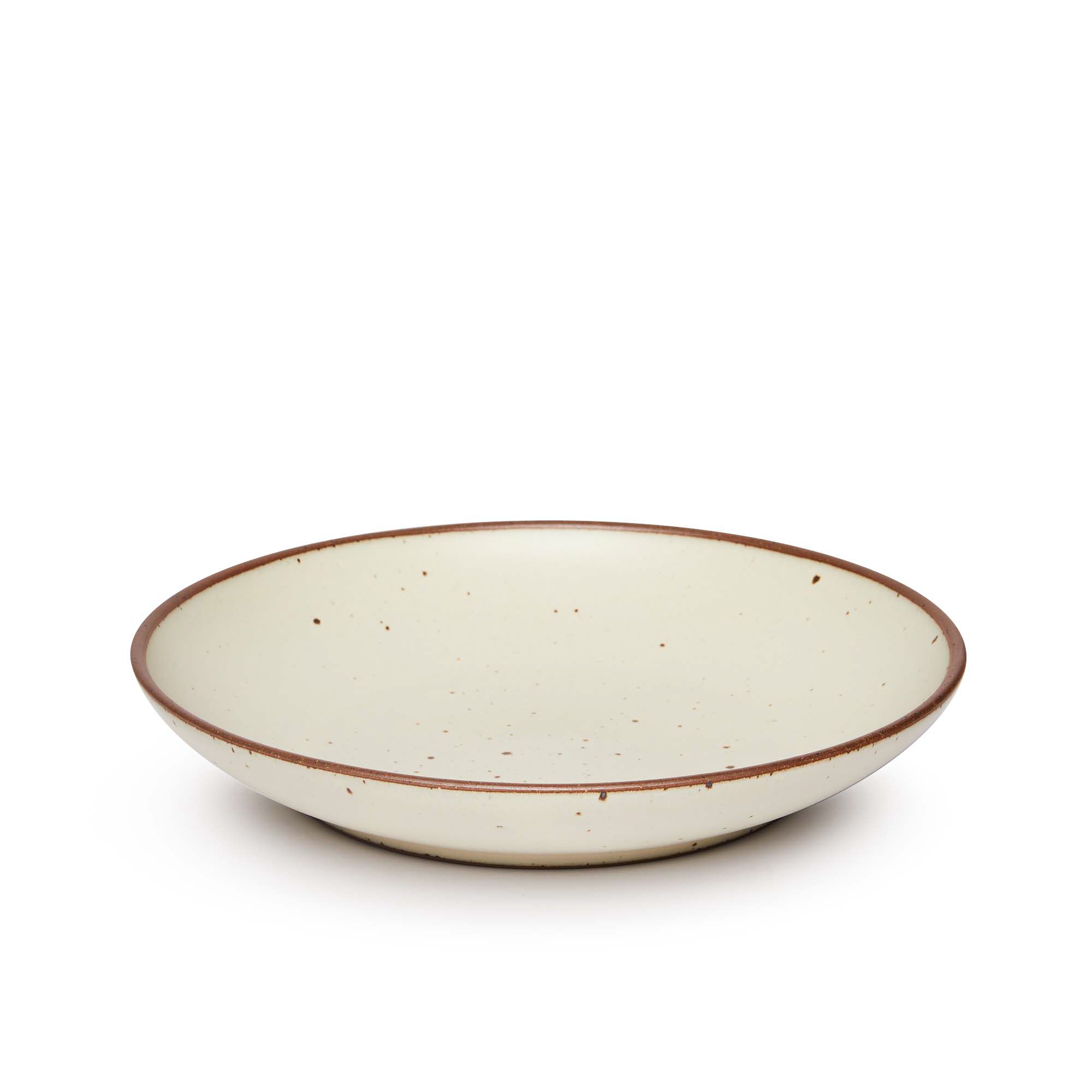 A large ceramic plate with a curved bowl edge in a warm, tan-toned, off-white color featuring iron speckles and an unglazed rim.