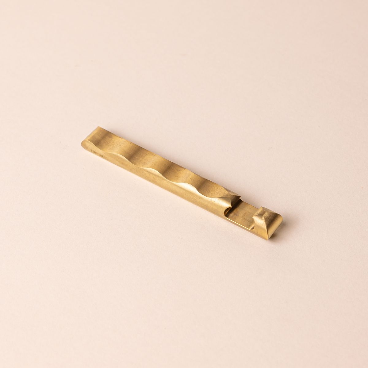 Sophisticated brass bottle opener with a simple design and a wave with grooves all along the opener side.