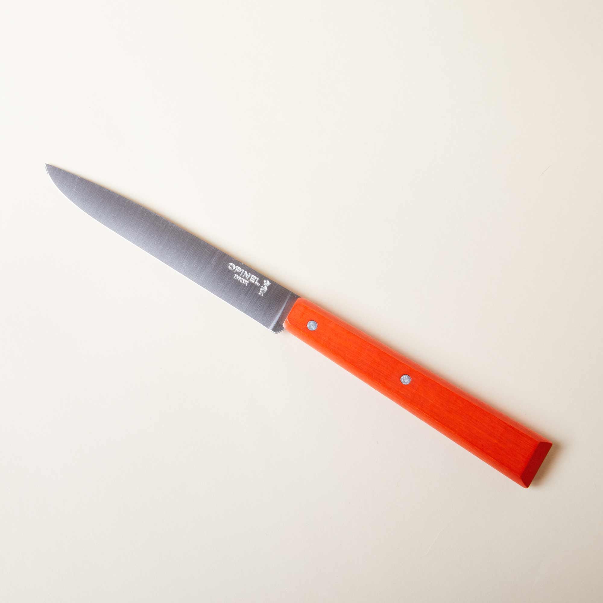 A steak knife with a bold orange handle