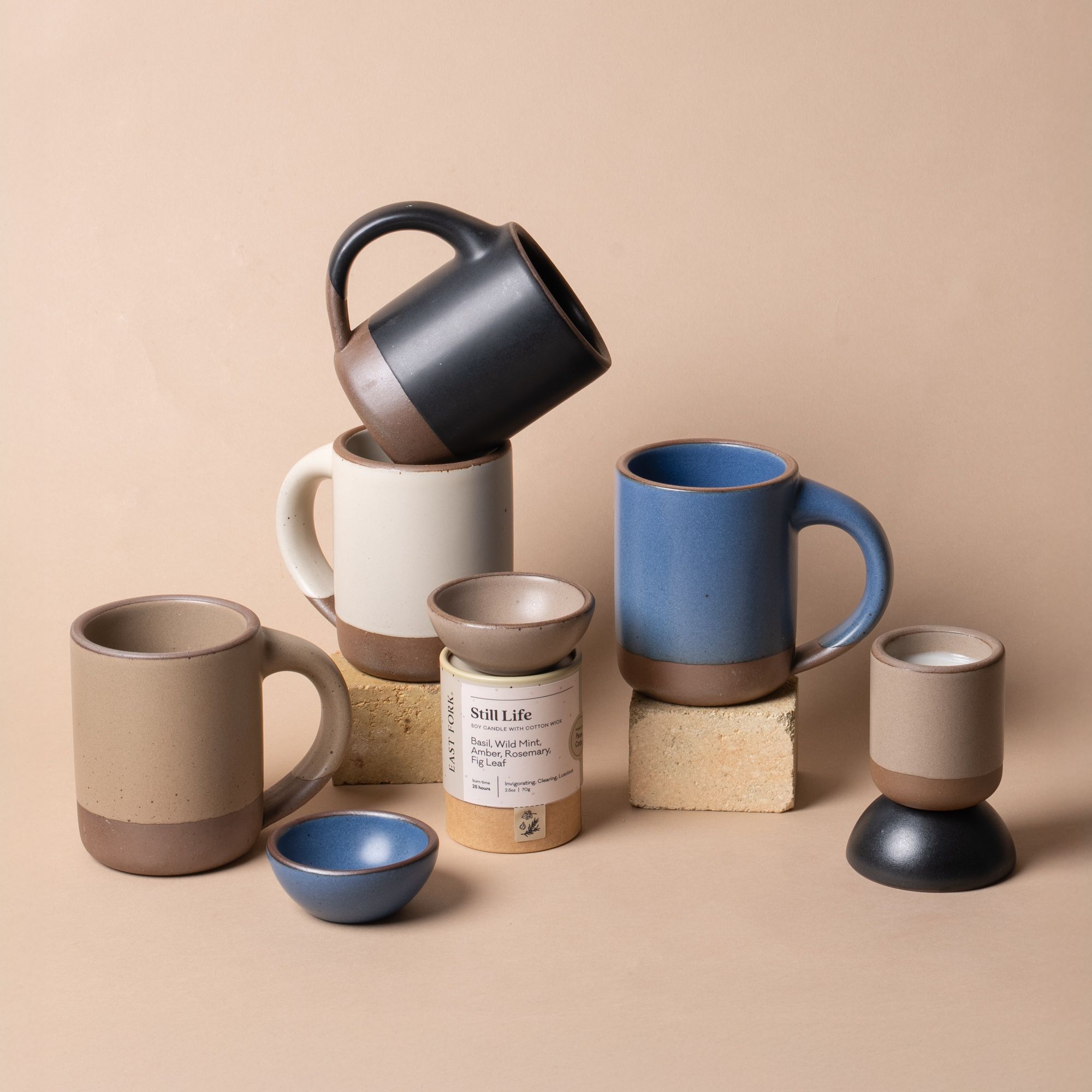 An entry table with a wooden tray with a candle, keys, and matches beside a blooming clematis and lush greenery.