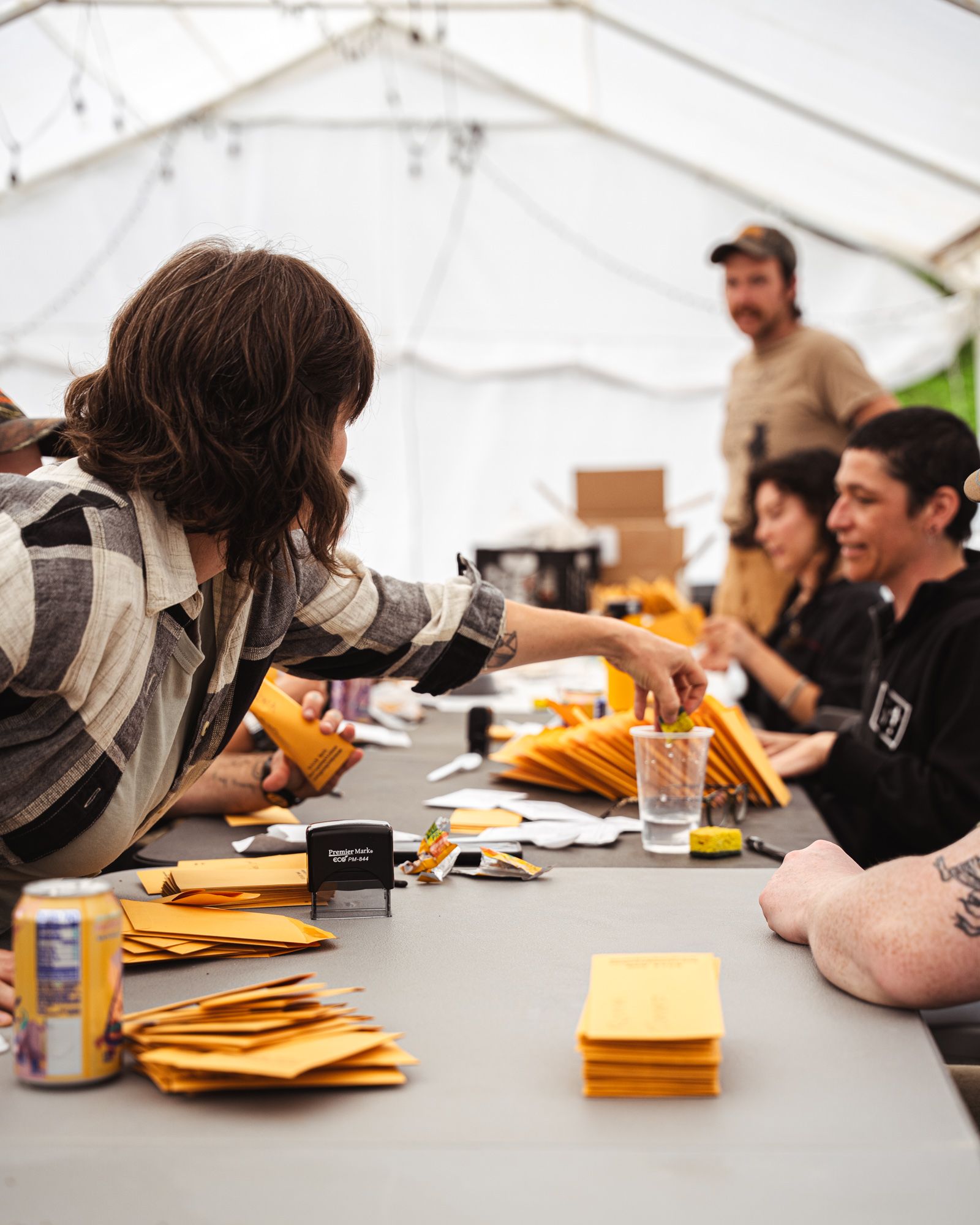 A bunch of people gathered around a table working on a project with manila envelopes