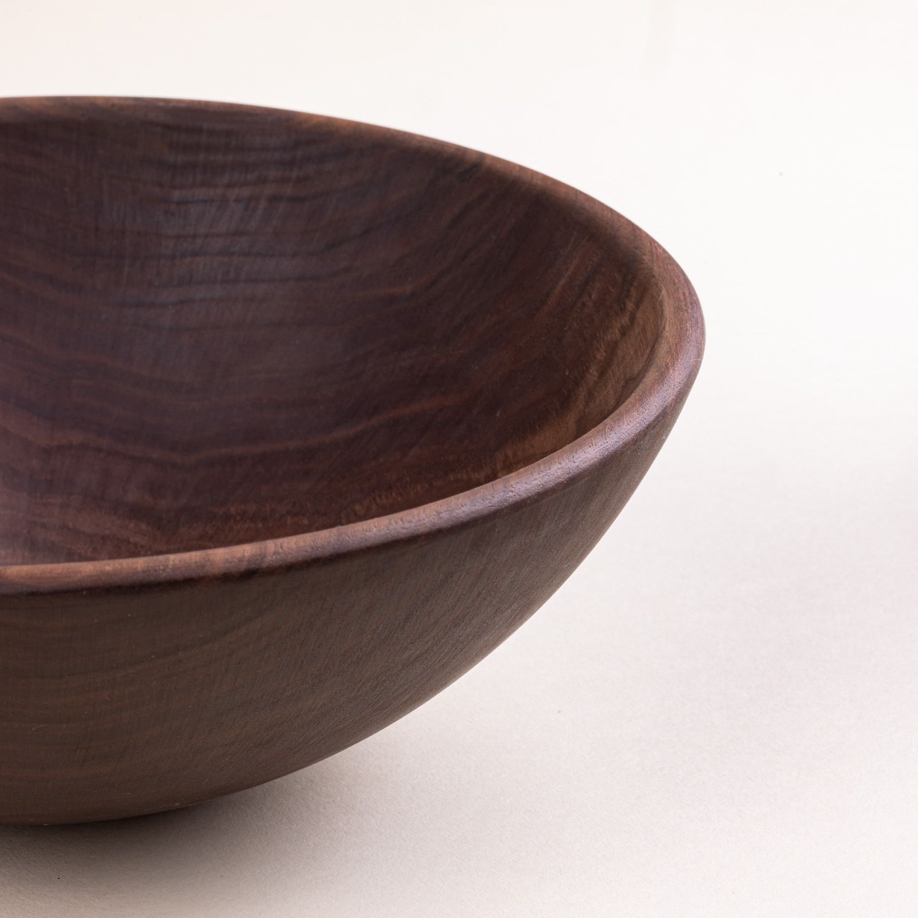 A closeup of the edge of a walnut wood bowl