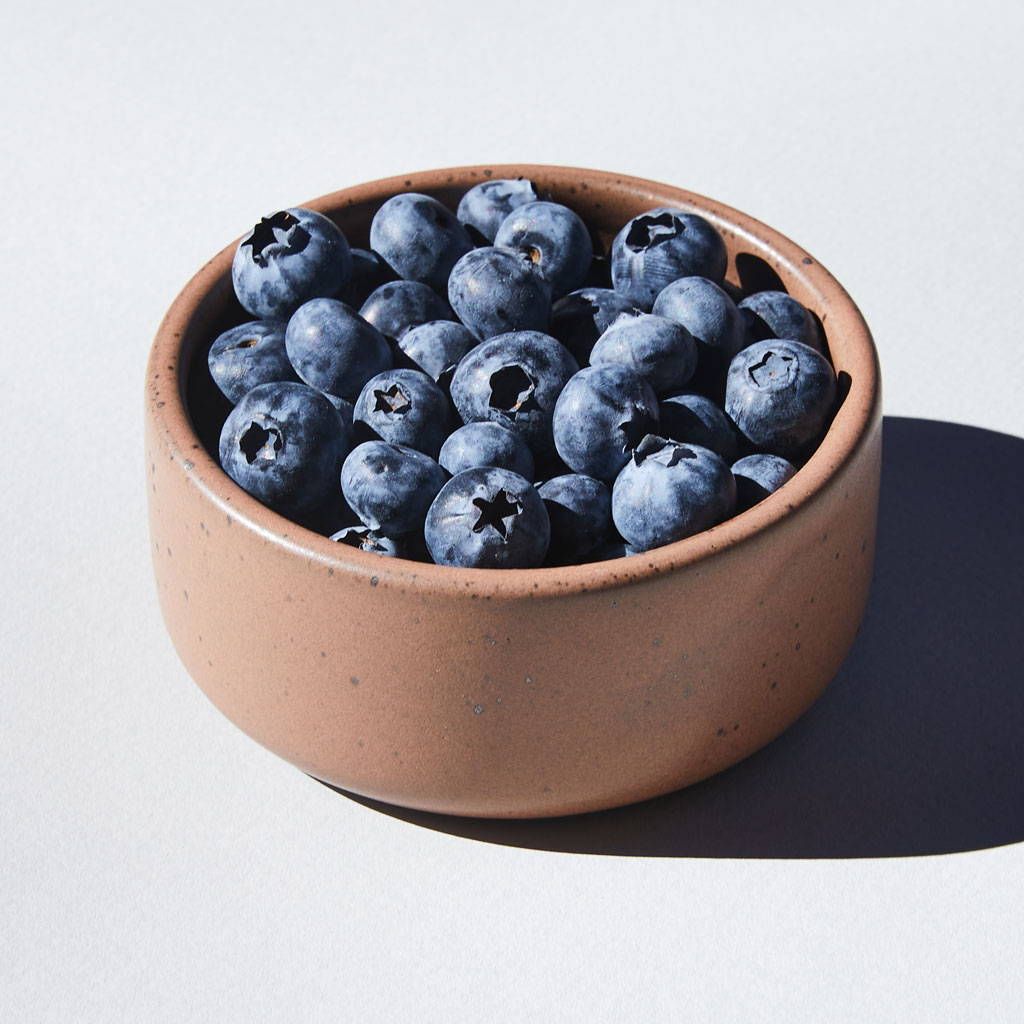 A ceramic ramekin in a earthy brown color with iron speckles and filled with blueberries