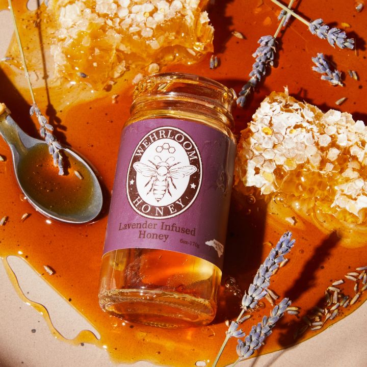 Honey on a plate with an empty jar, honeycomb, lavender and a spoon.