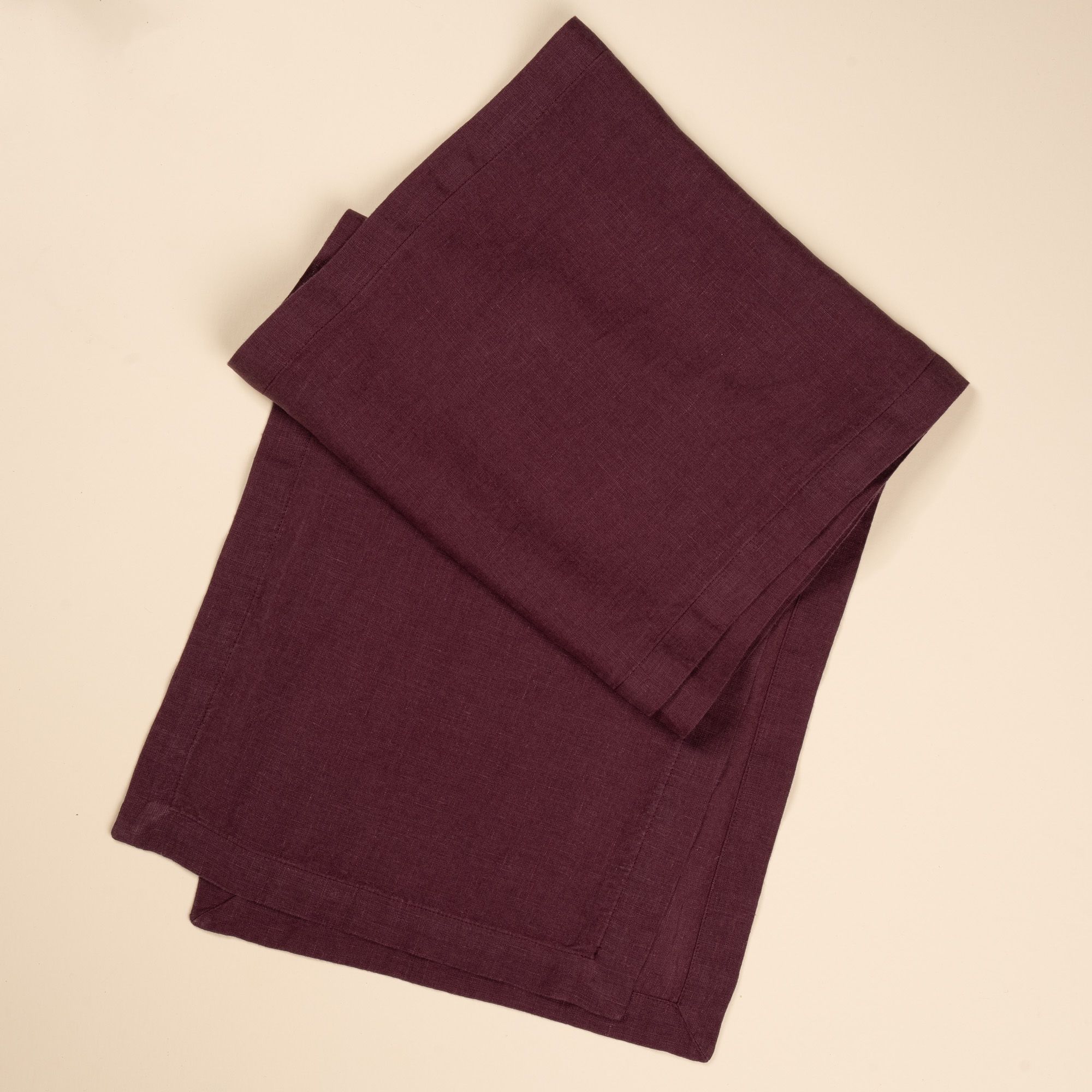 A folded linen table runner in a deep purple color