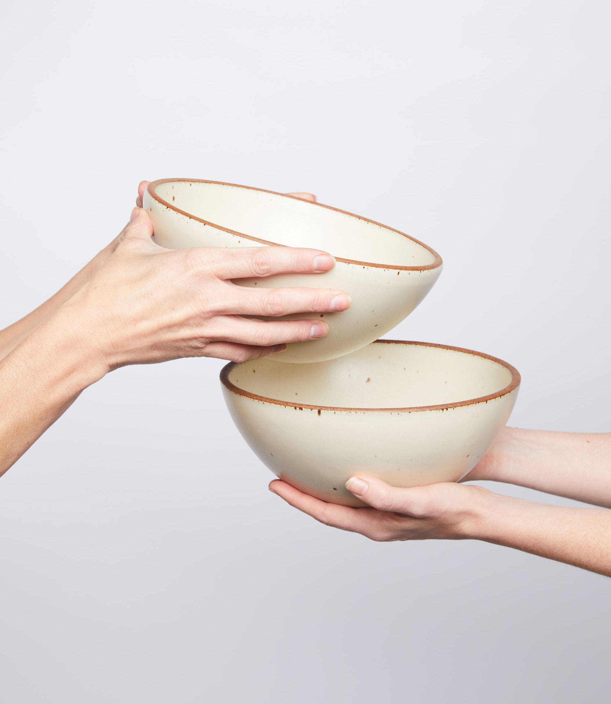 two sets of hands passing panna cotta bowls 
