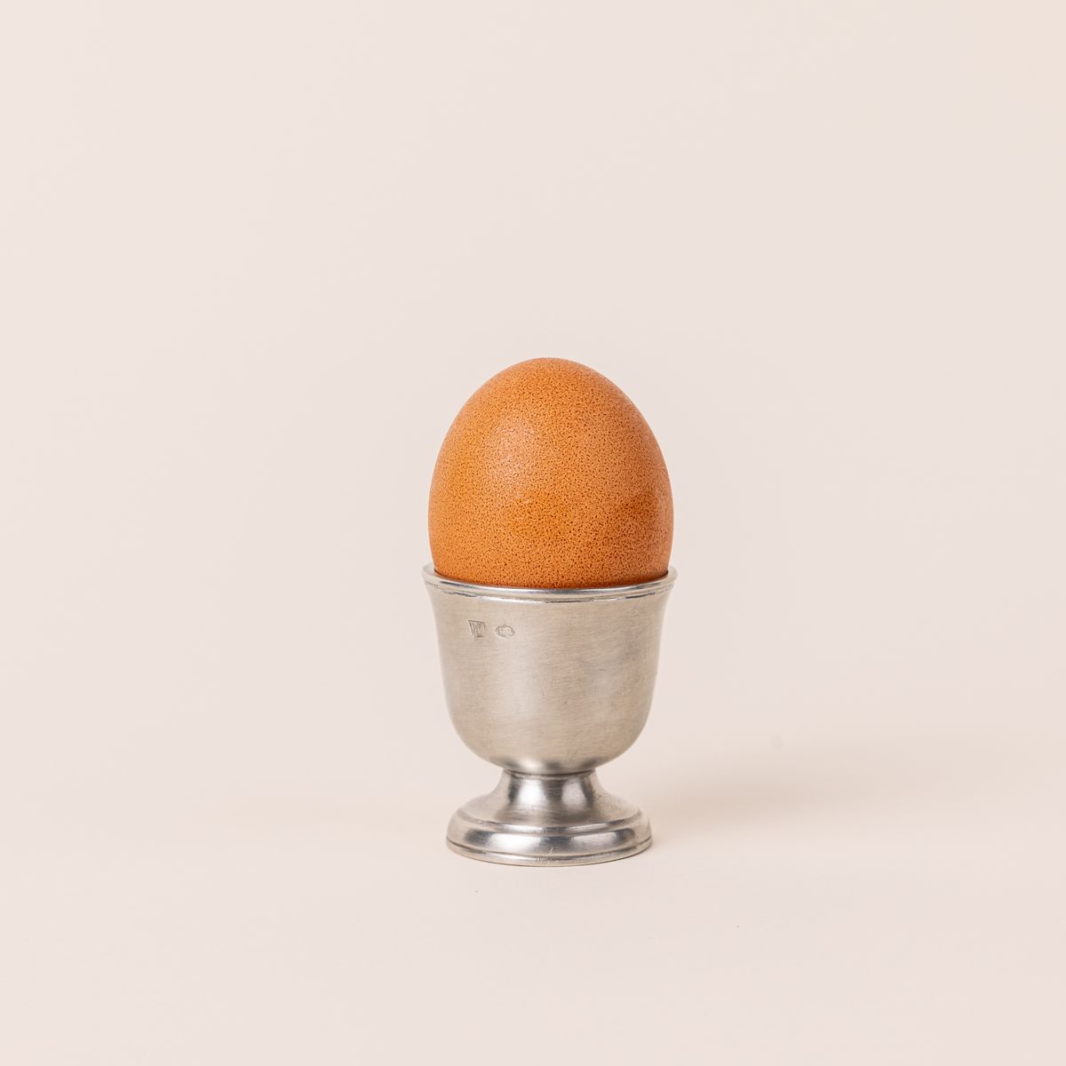 Egg inside a traditional egg cup in a silver pewter and shaped like a small goblet.