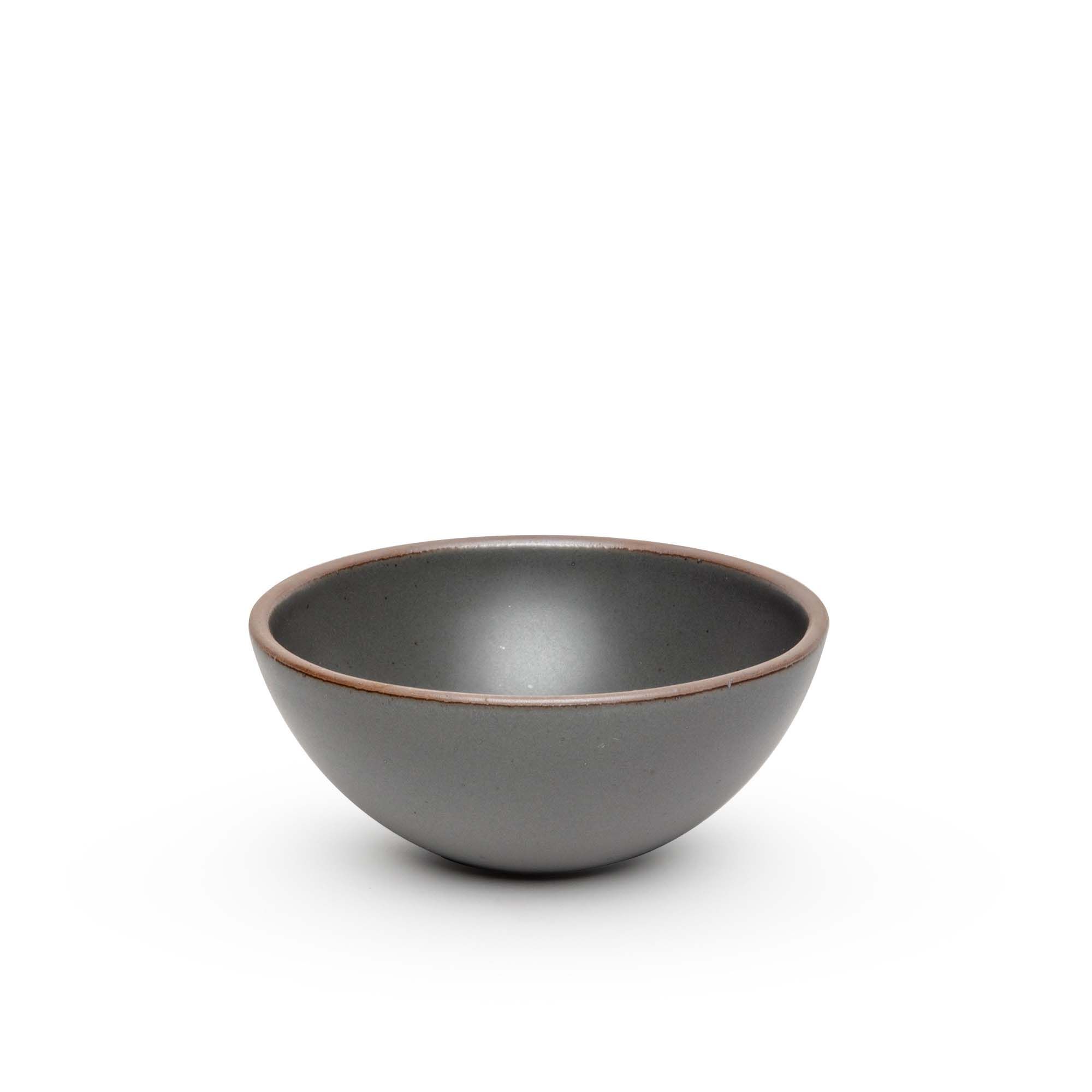A medium rounded ceramic bowl in a cool, medium grey color featuring iron speckles and an unglazed rim