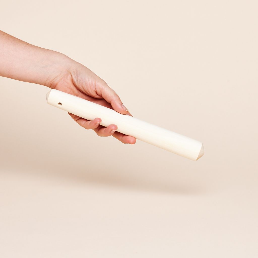Long, narrow white pestle held in a hand