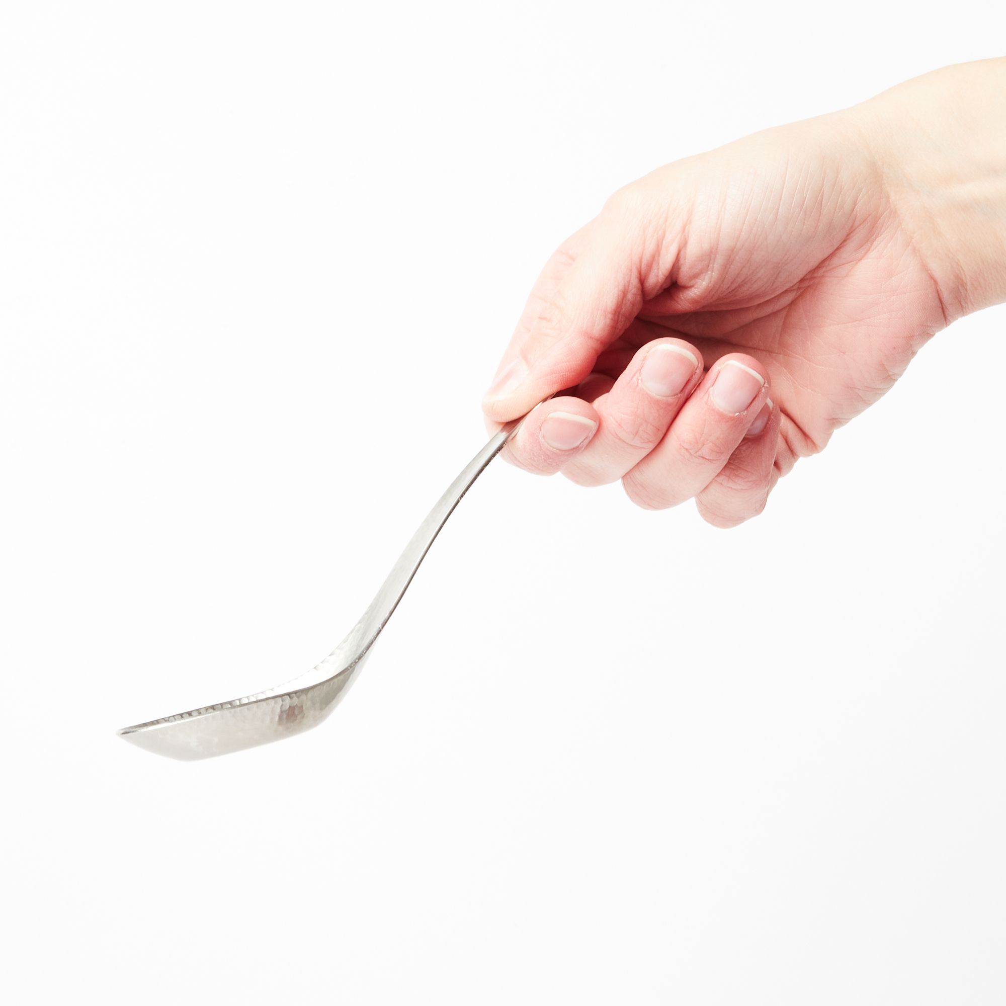 A hand holding a steel Asian soup spoon with hammered finish