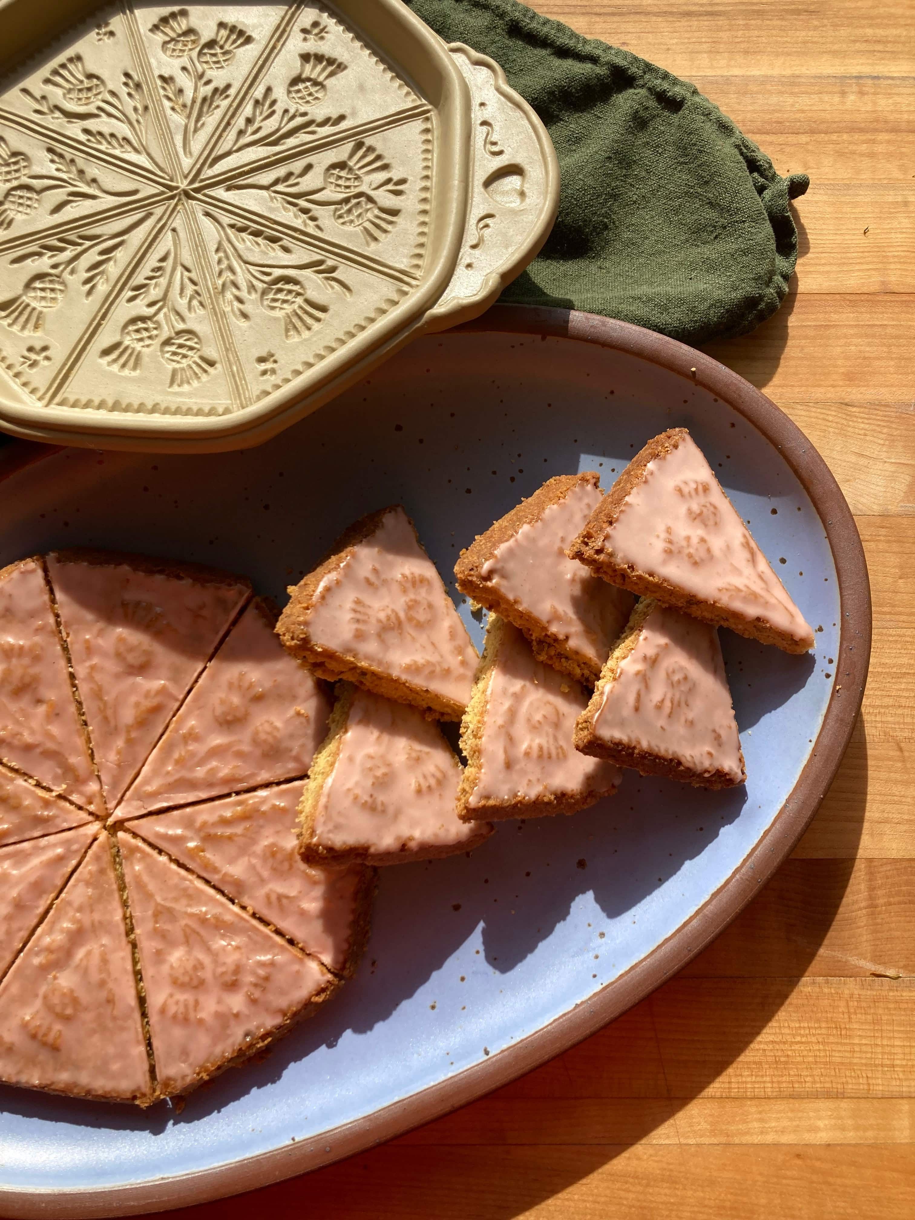 Pistachio shortbread plated in a periwinkle oval platter with a shortbread pan next to it in the corner.