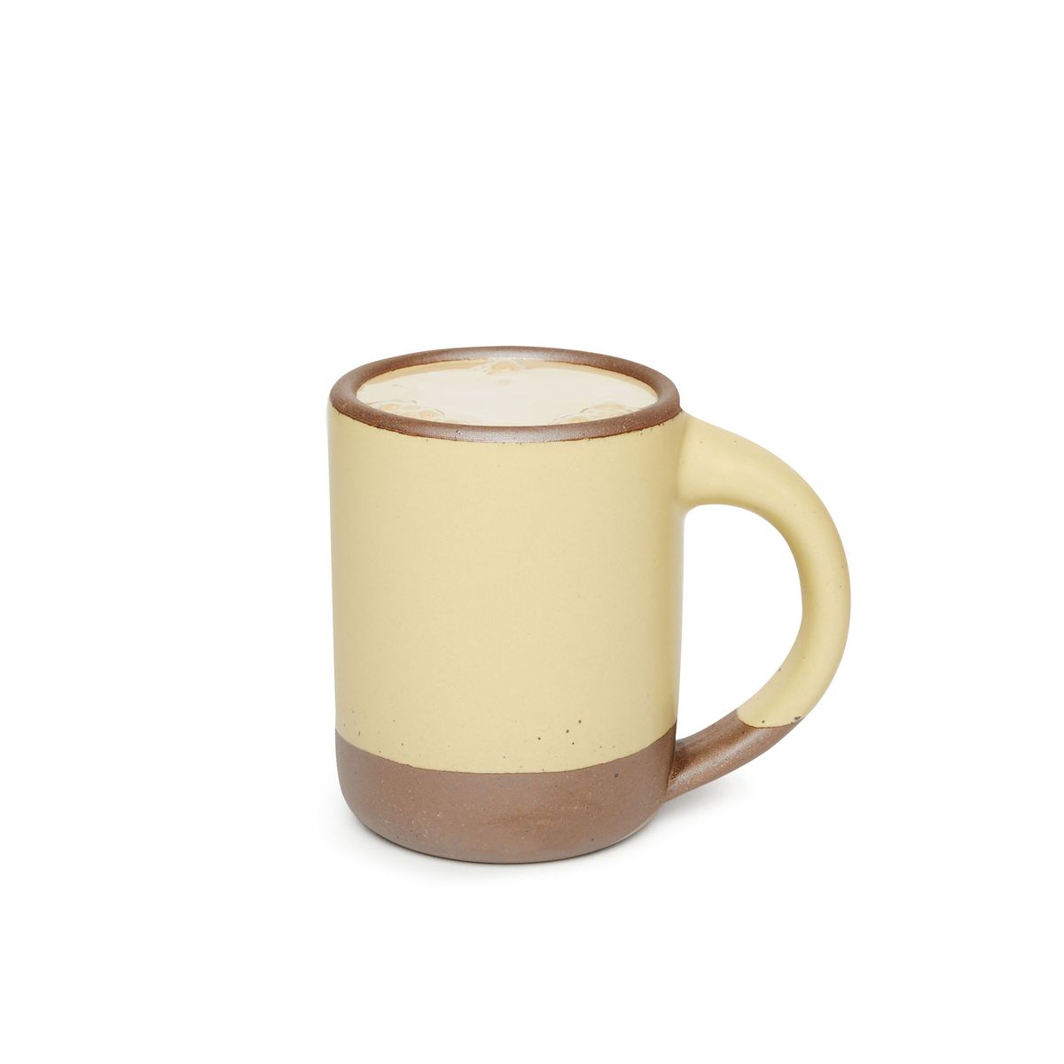A medium sized ceramic mug with handle in a light butter yellow color featuring iron speckles and unglazed rim and bottom base, filled with light coffee.