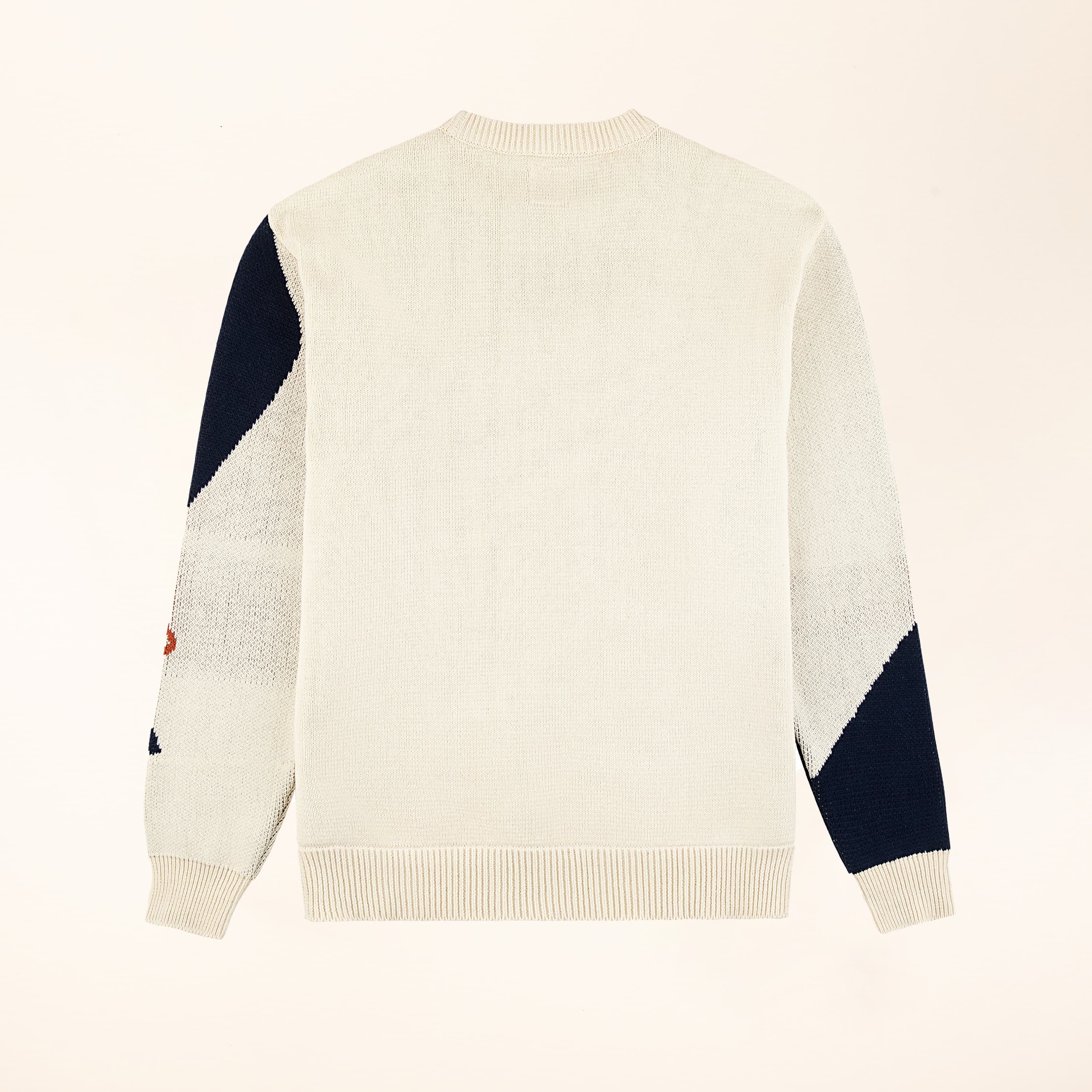 A flatlay of the back of a sweater with in cream with some navy blocks of color on the sleeves.