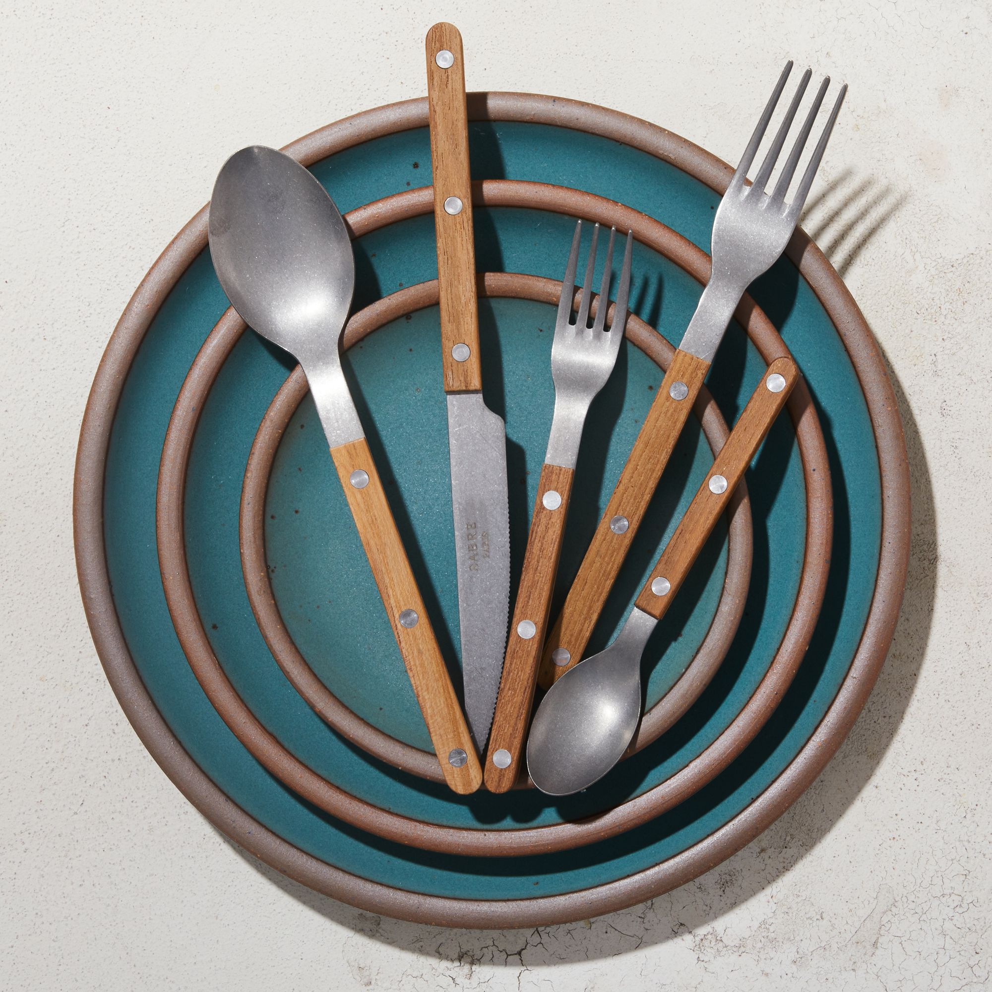 Silverware set with teak handles on Secret Beach Plate stack