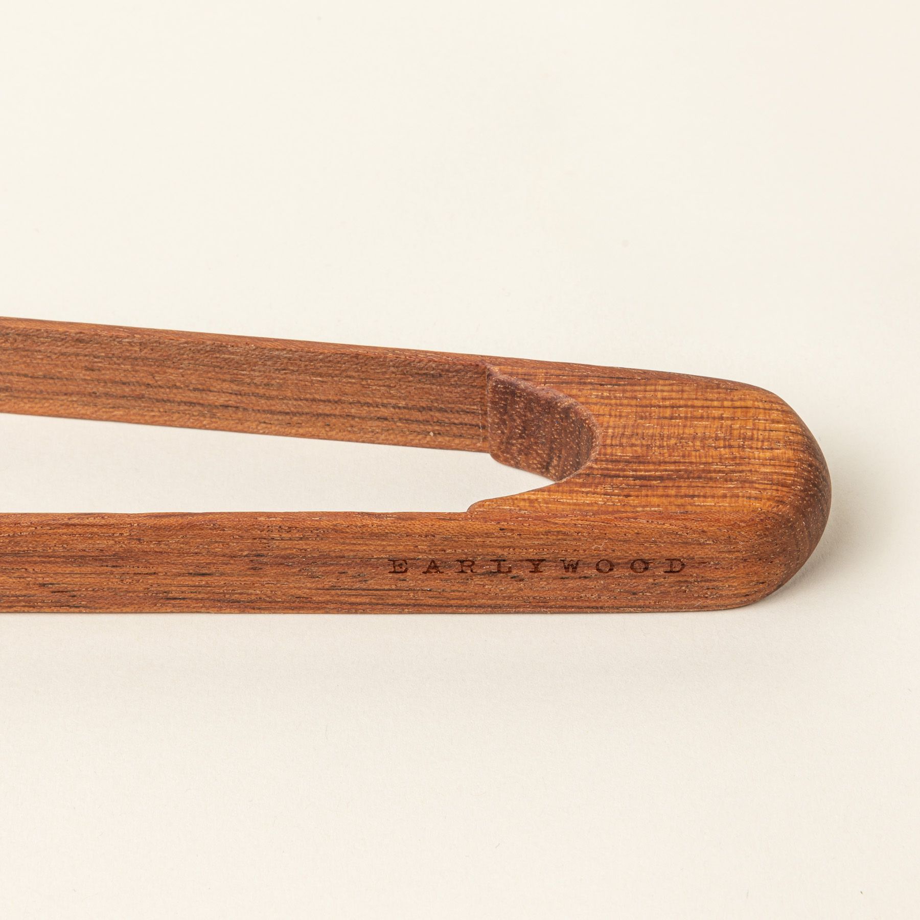 A close up of the end of a simple and minimal wood rectangular tongs