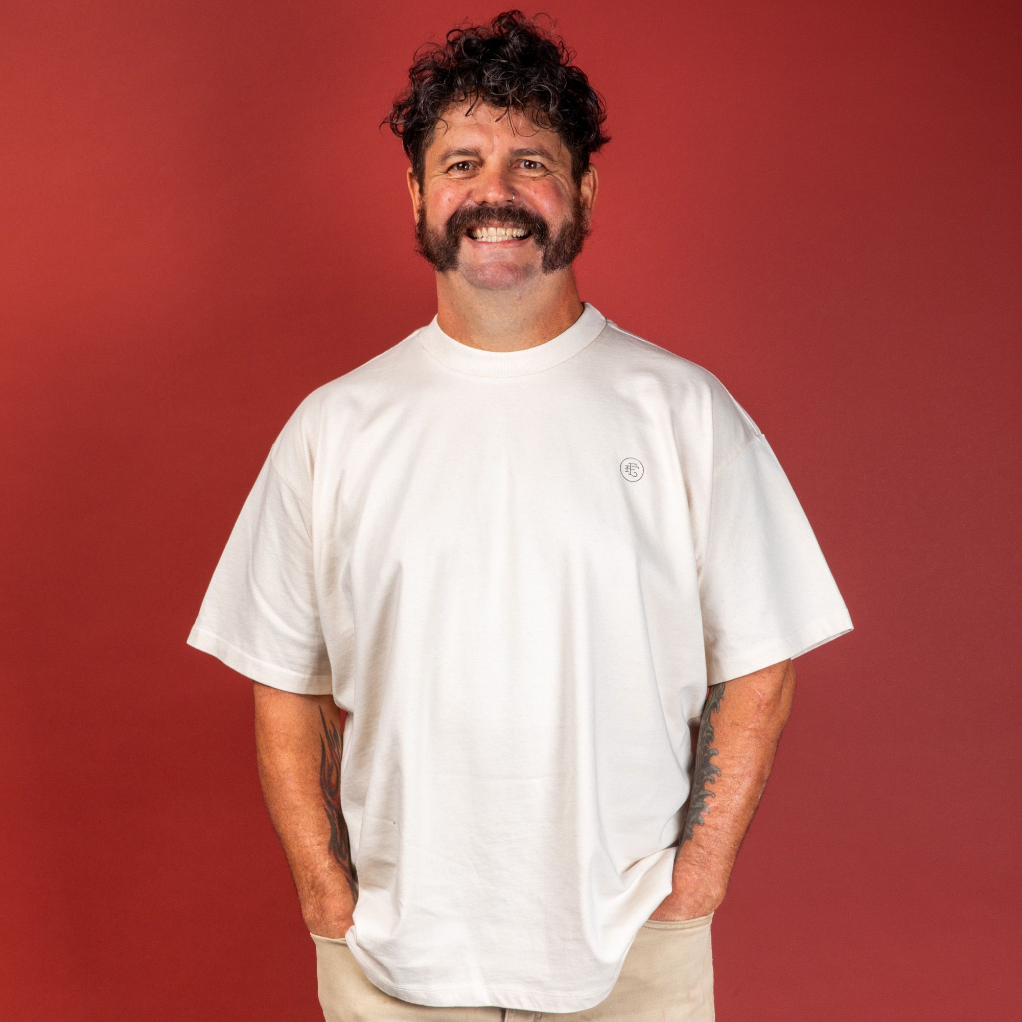 Model wearing the t-shirt and smiling at the camera with hands in front pockets.