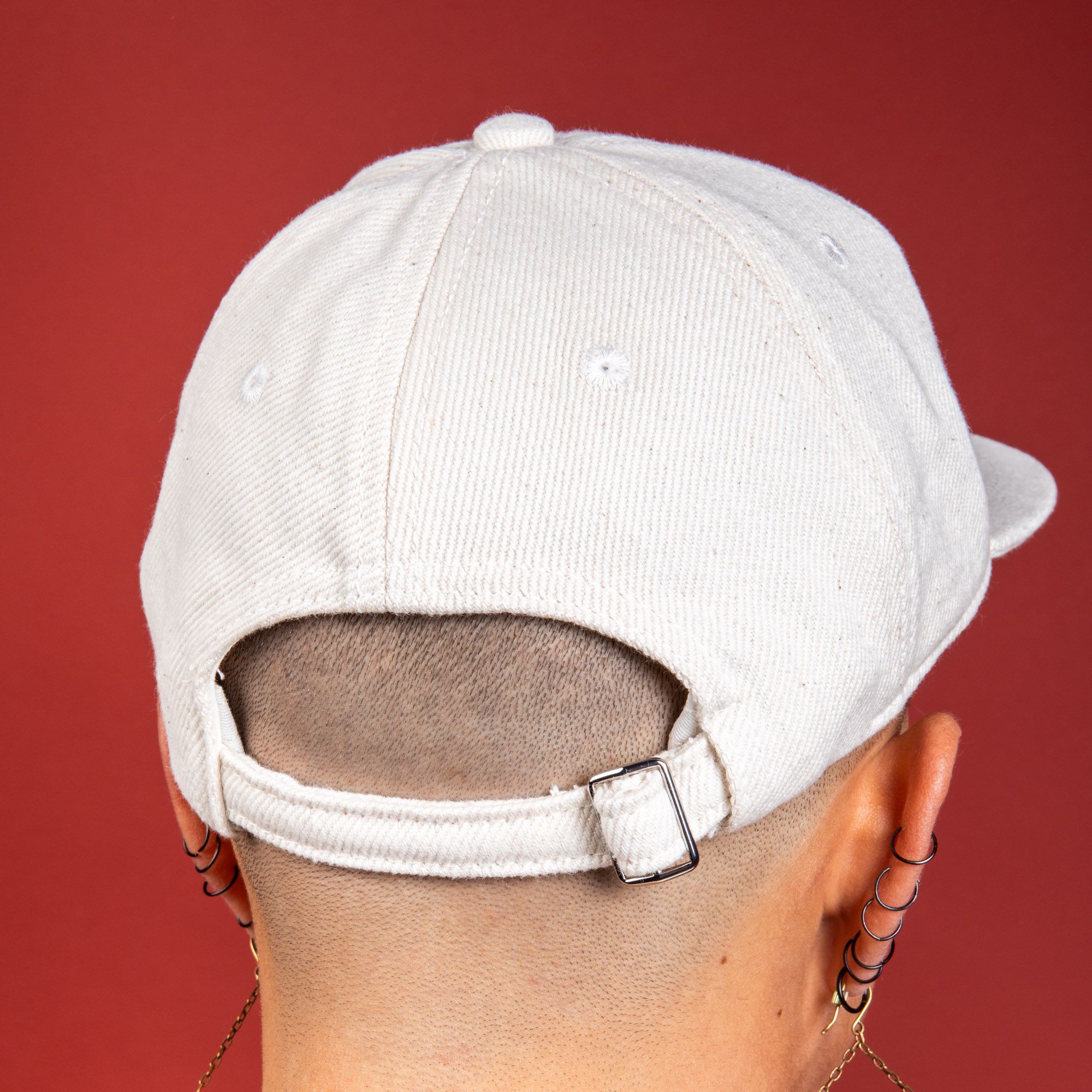 Close up of the back of a white denim baseball hat being worn