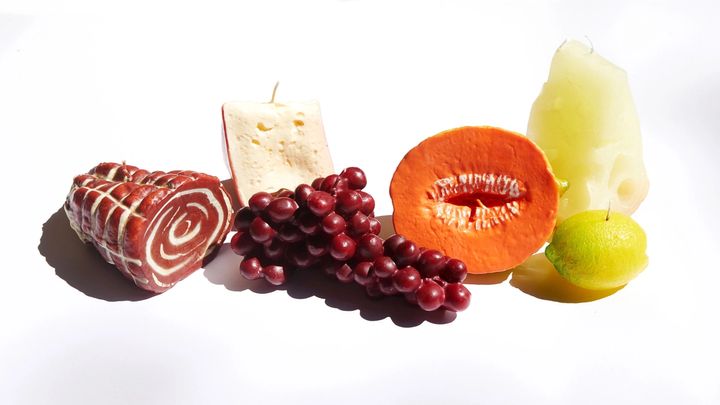 Assortment of candles that look like real meat, cheese, veggies and fruits. But they're made of wax!