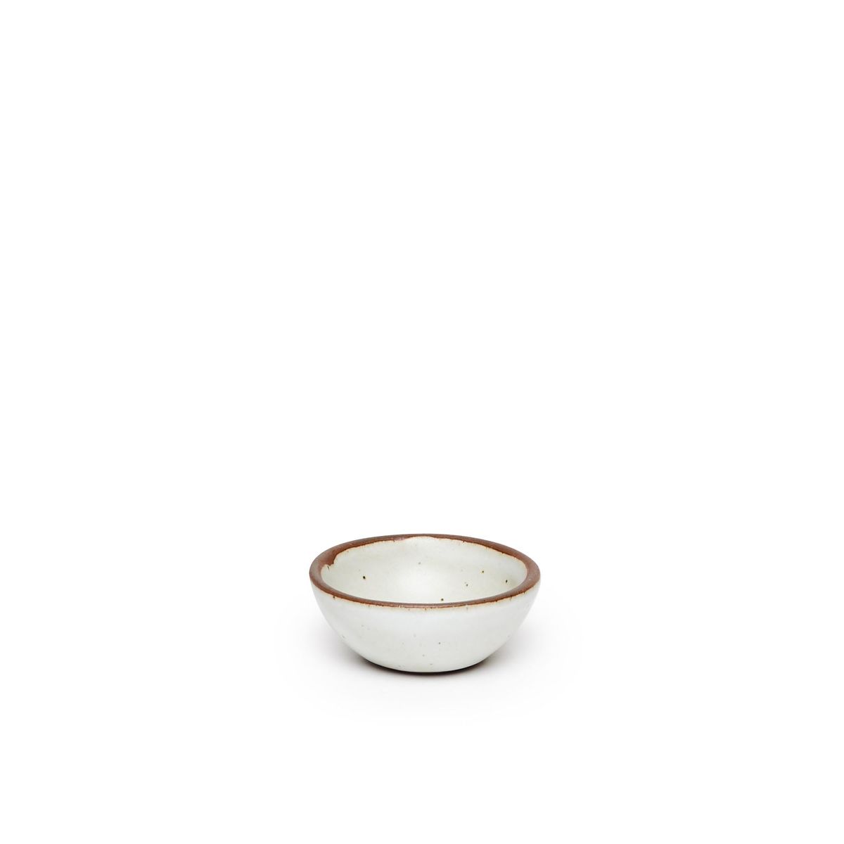 A tiny rounded ceramic bowl in a cool white color featuring iron speckles and an unglazed rim