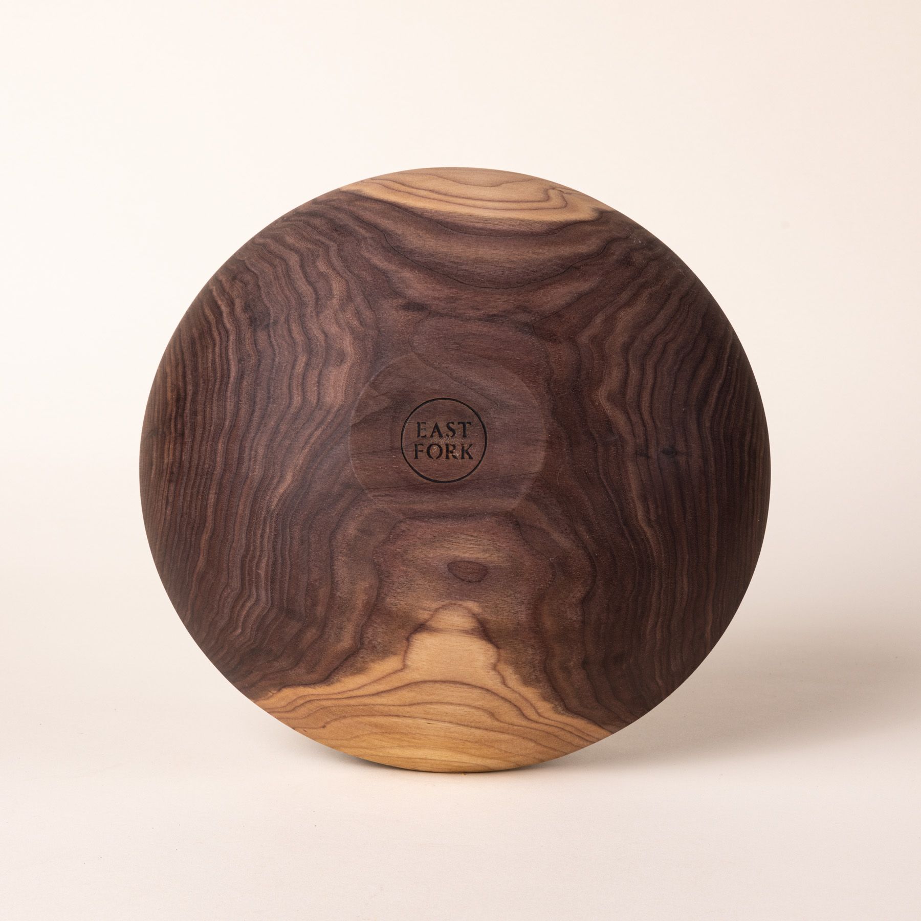 The bottom of a large walnut wood bowl with a stamp that reads "East Fork"