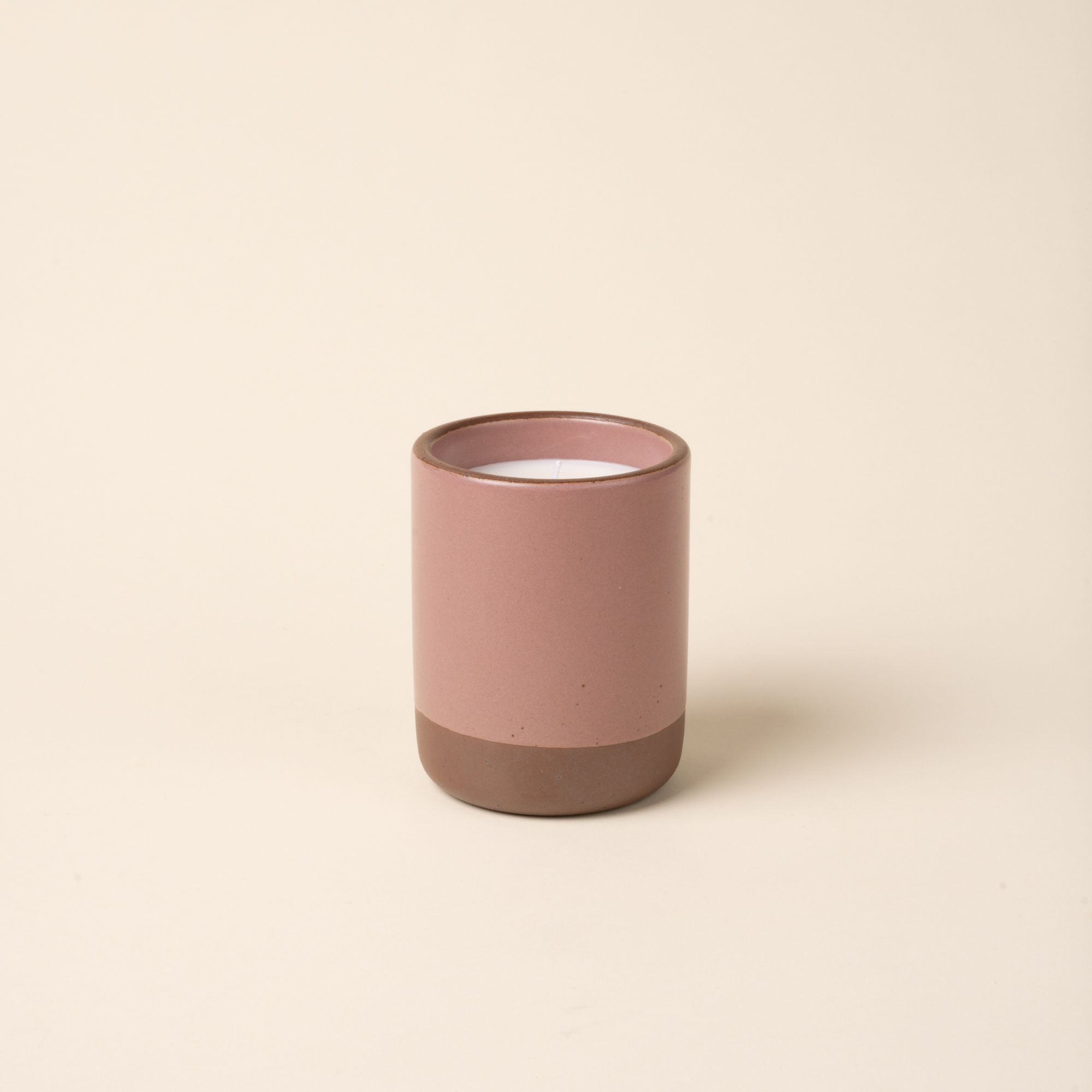 Large ceramic vessel in a soft mauve pink color with poured candle inside.