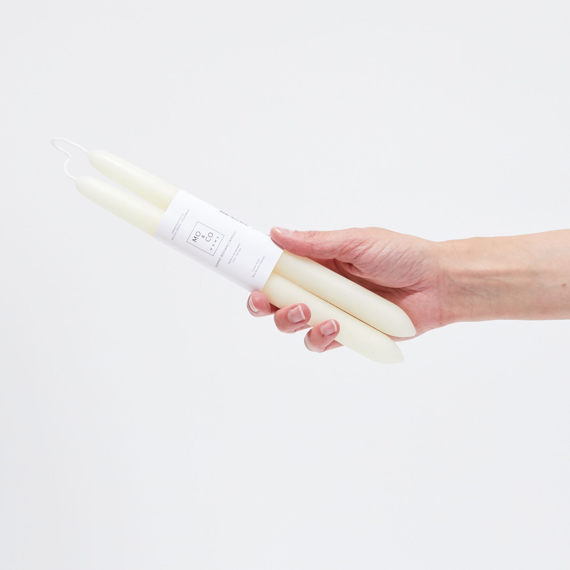 hand holding ivory taper candles with white label