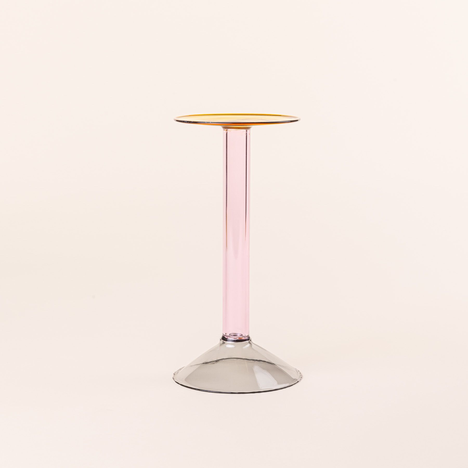 A tall modern angular glass candle holder in yellow, pink, and grey colorblocks