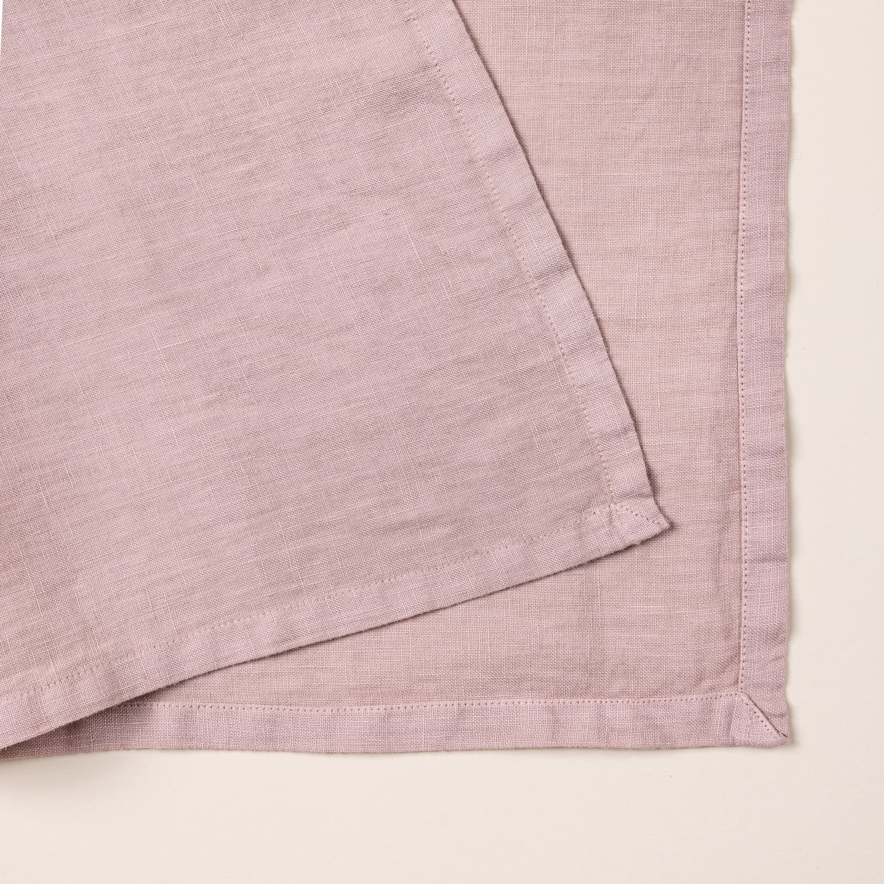 A closeup of a folded linen napkin in a soft pink color