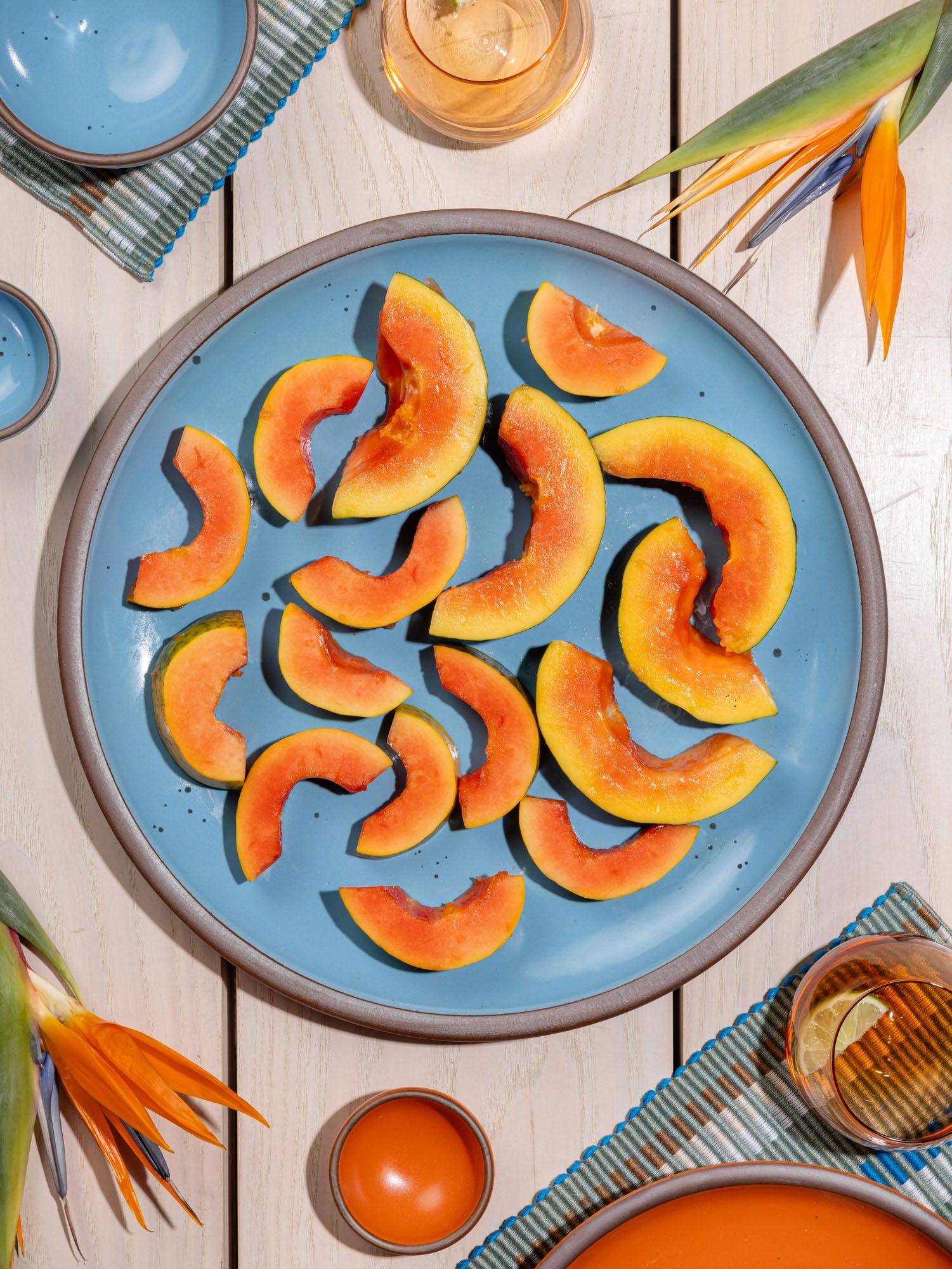 Sliced papayas are on a large ceramic platter in a robin's egg blue color featuring iron speckles and an unglazed rim