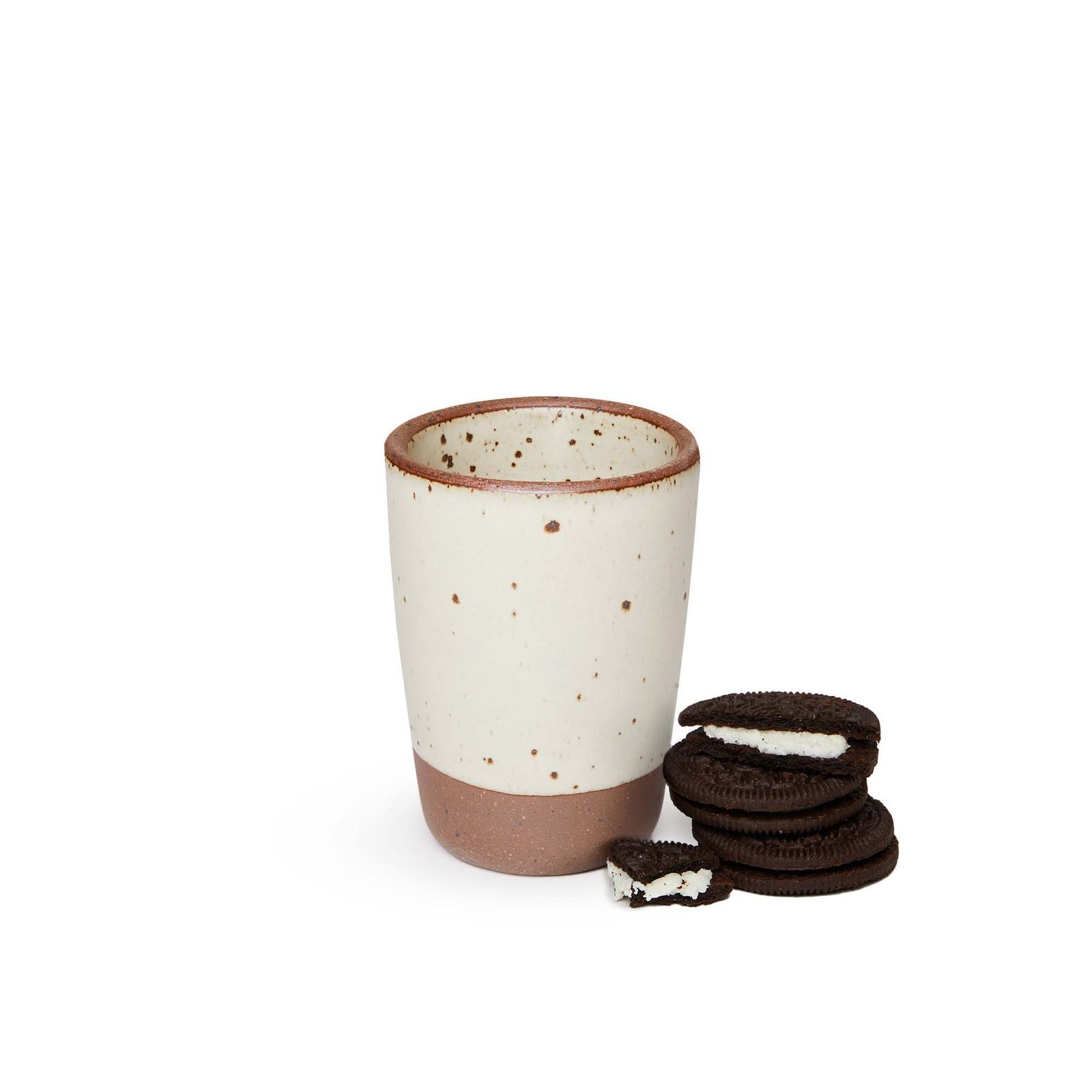 An off-white juice cup with a small stack of three Oreos beside it. Yes, this is the perfect vessel for dunking!