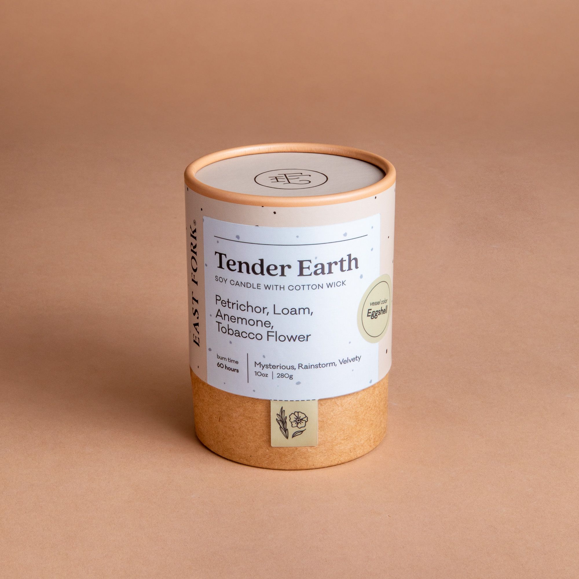Large cardboard packaging tube with a candle inside with branding on it that says 'Tender Earth'