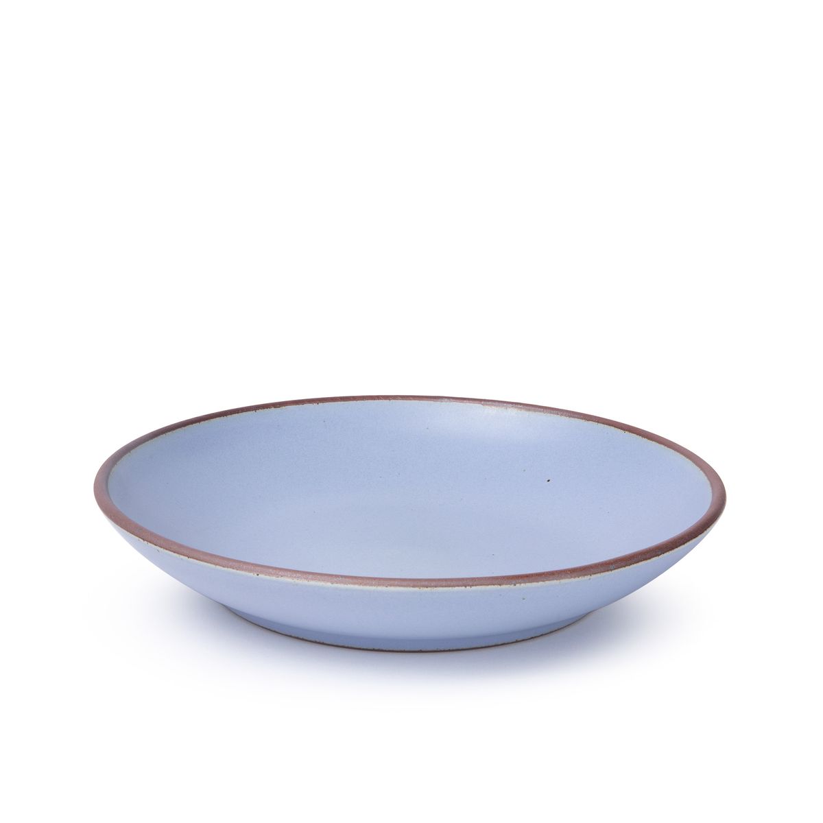 A large ceramic plate with a curved bowl edge in a periwinkle color featuring iron speckles and an unglazed rim.