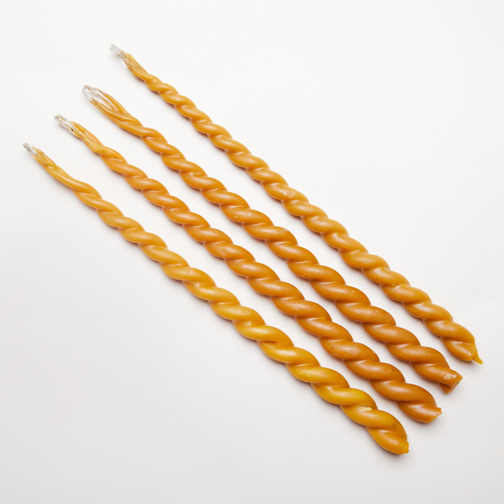 Four long twisted candles in various shades of golden yellow