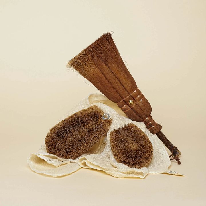 Two East Fork Plates - a side plate and dinner plate - sit underneath two brooms of varying size.