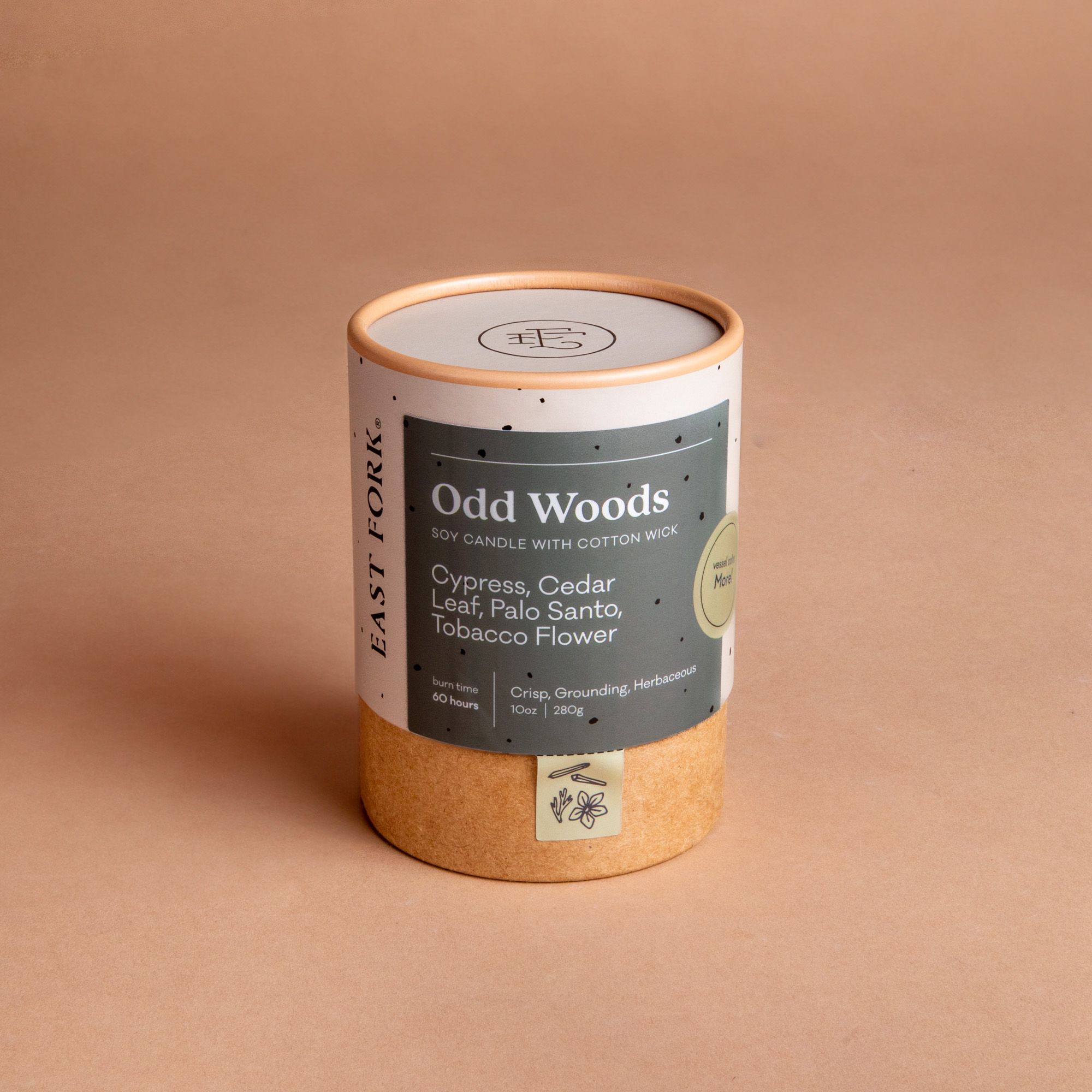 Large cardboard packaging tube with a candle inside with branding on it that says 'Odd Woods'