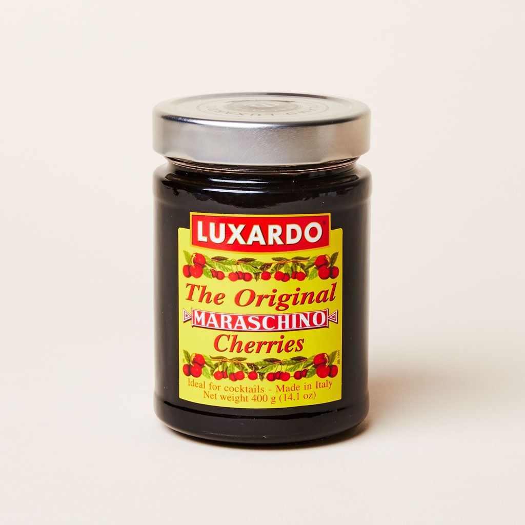 A glass jar containing a dark substance with a silver lid and yellow and red label that reads "Luxardo The Original Maraschino Cherries"