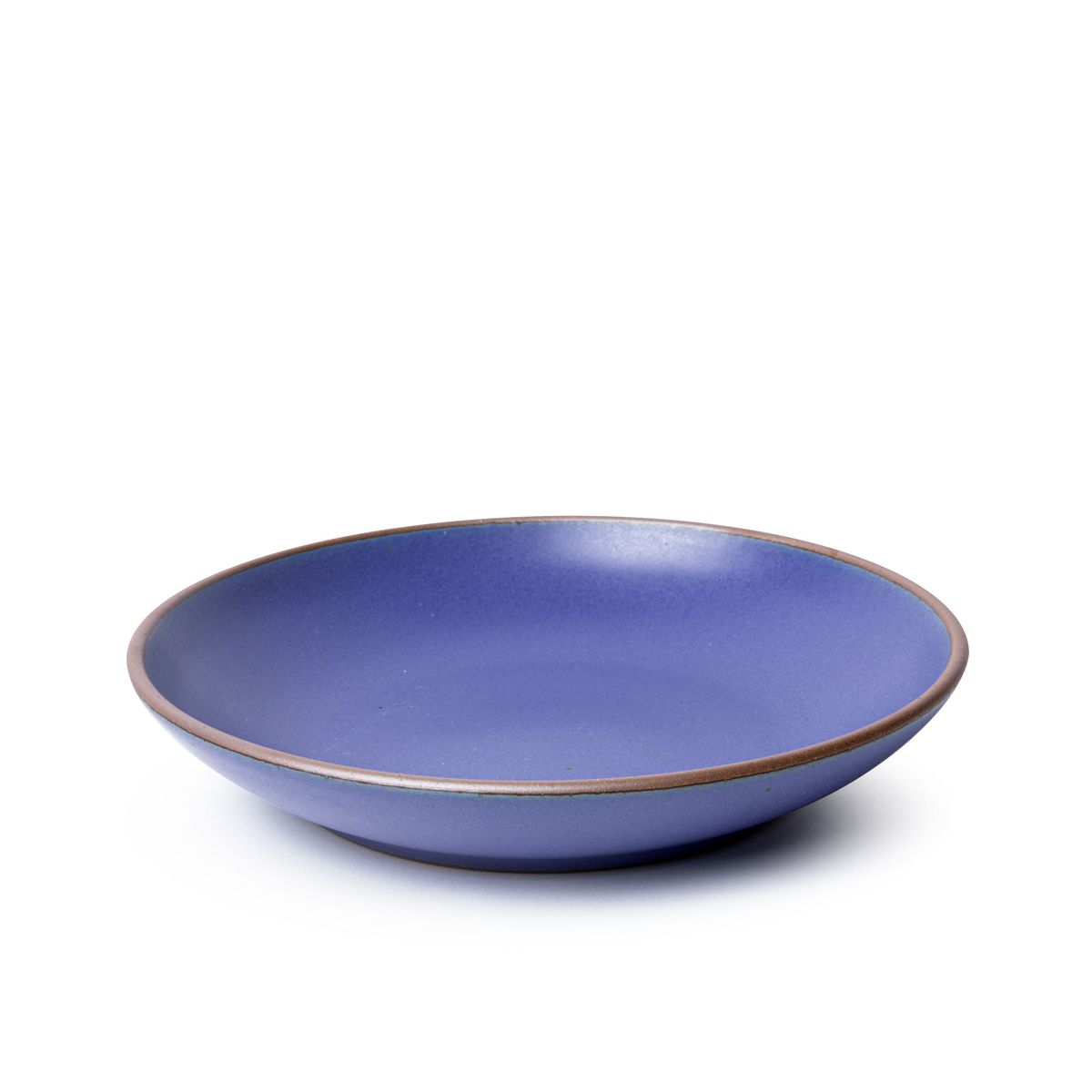 A large ceramic plate with a curved bowl edge in a true cool blue color featuring iron speckles and an unglazed rim.