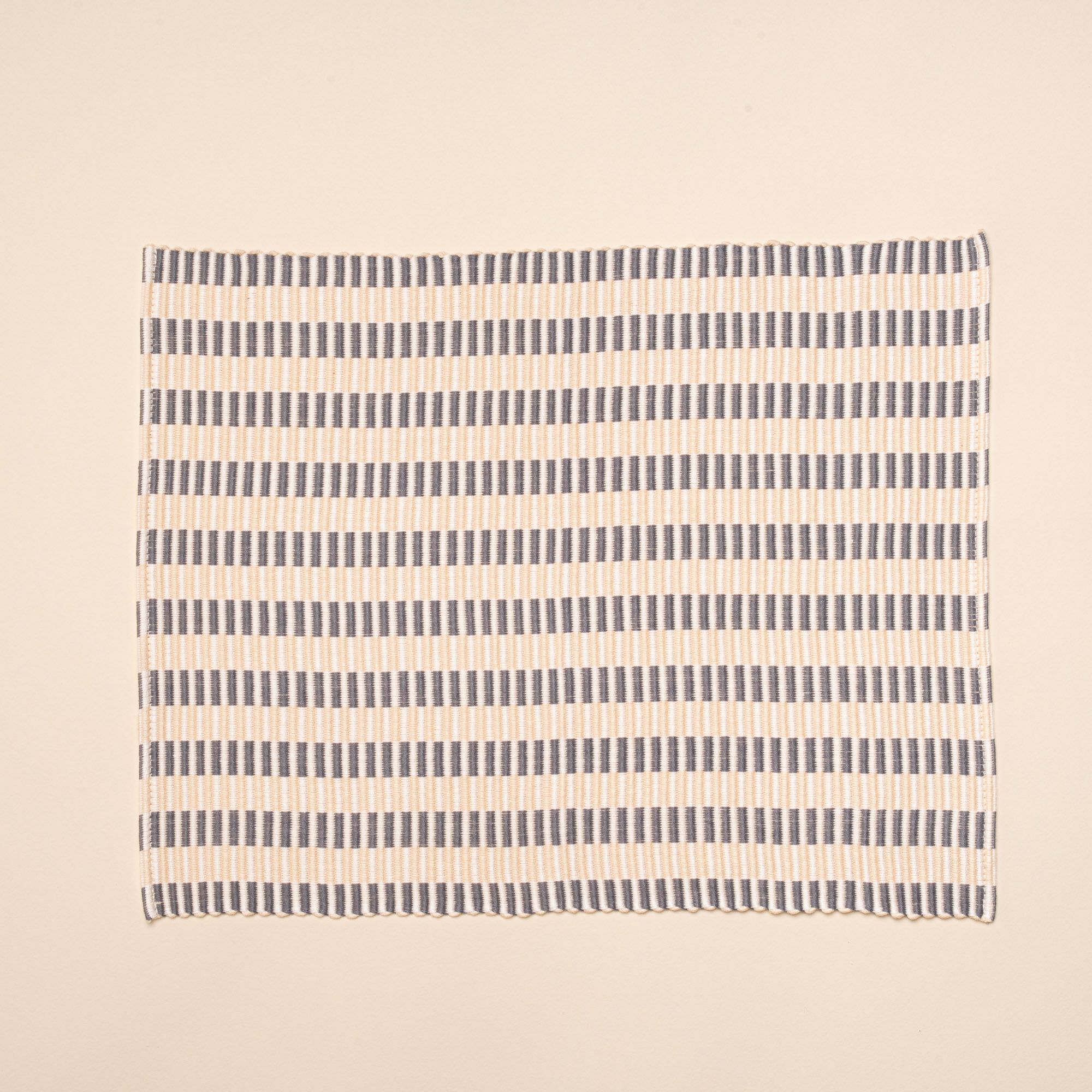 A woven placemat with thin horizontal striped grey and natural colors