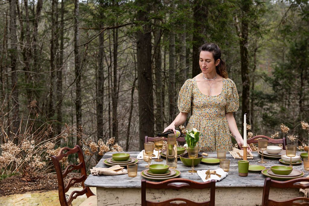 Connie Matisse standing at table outdoors, pouring wine 