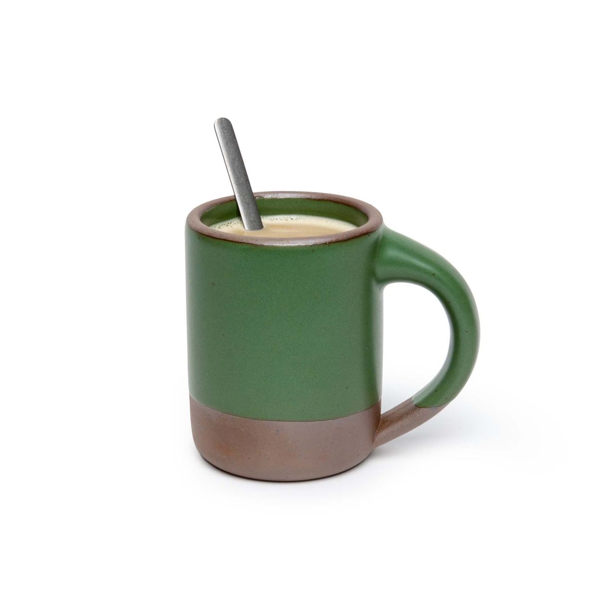 A medium sized ceramic mug with handle in a deep, verdant green color featuring iron speckles and unglazed rim and bottom base, filled with coffee and spoon