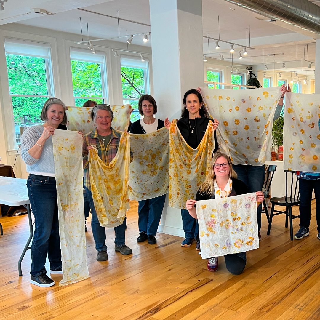 In the East Fork Asheville Store, students hold up silk scarves that are eco-printed.