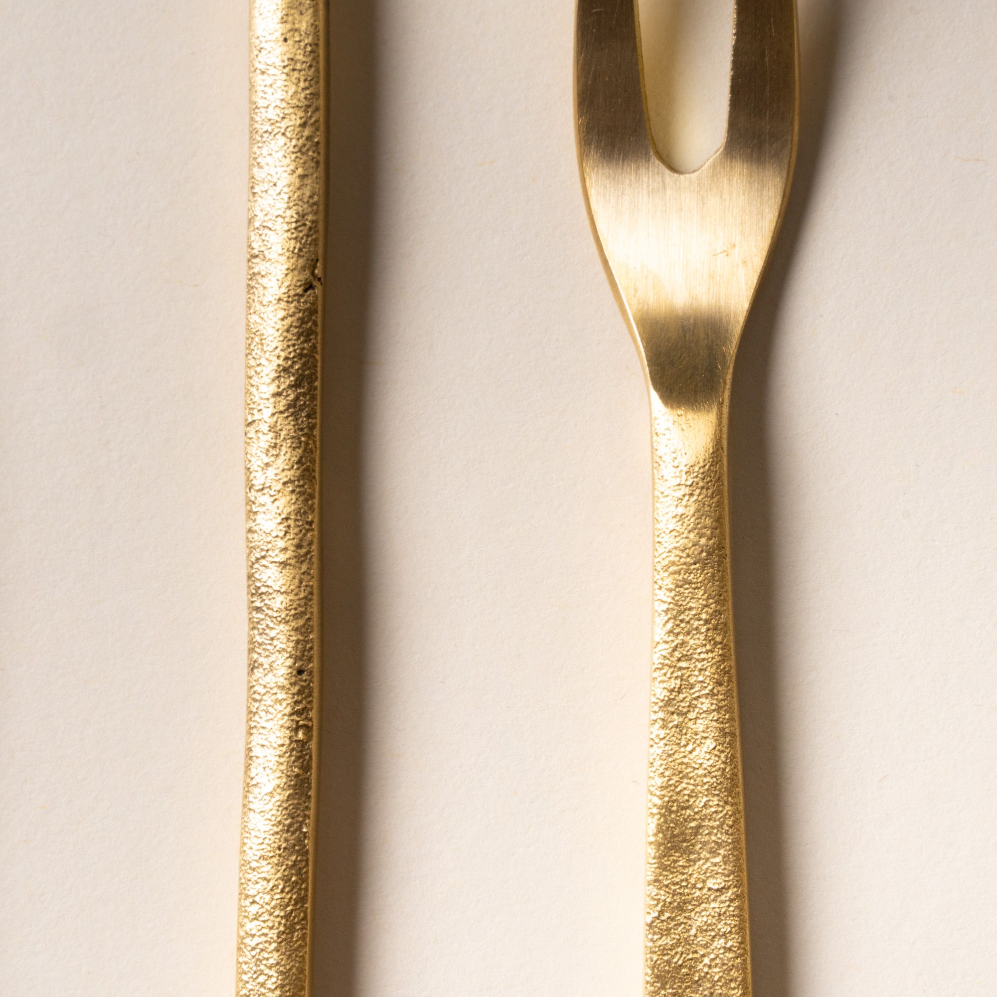 Close up of brass flatware utensils arranged on a light background