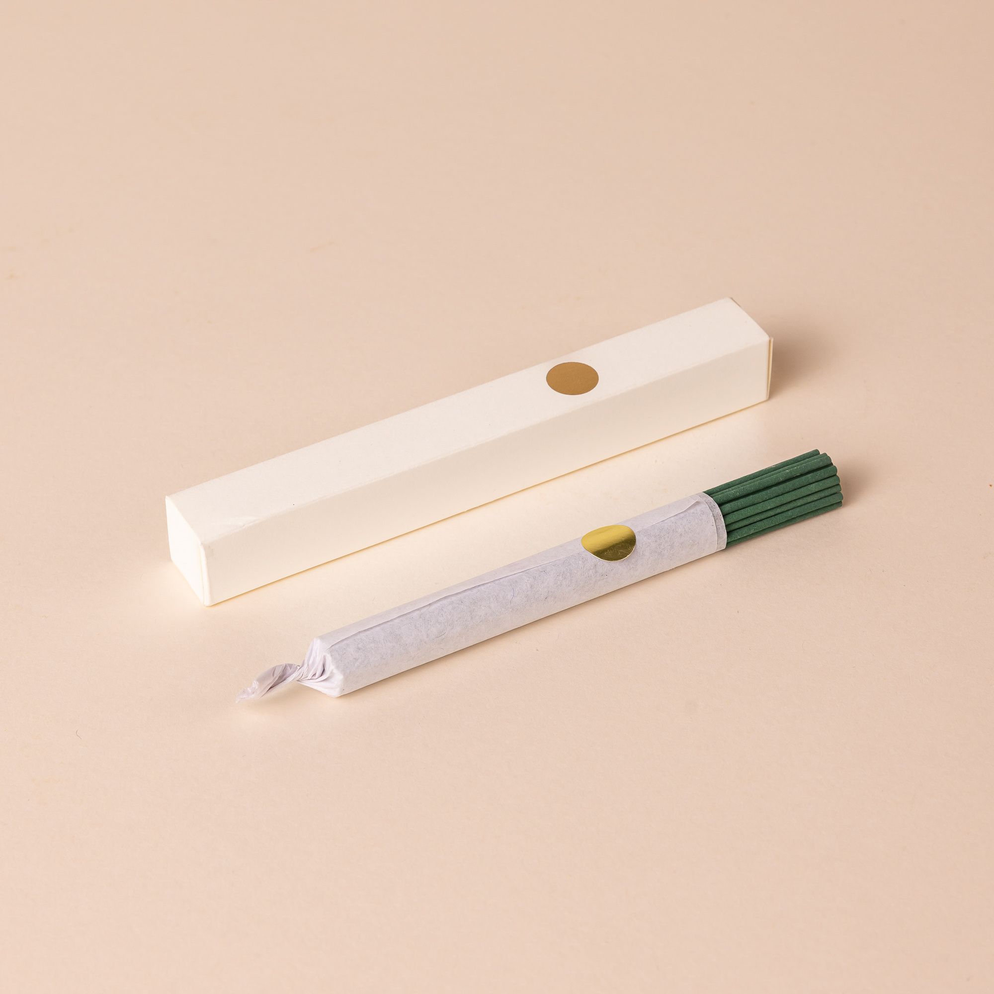 A bundle of teal incense sticks wrapped is next to a thin white box.