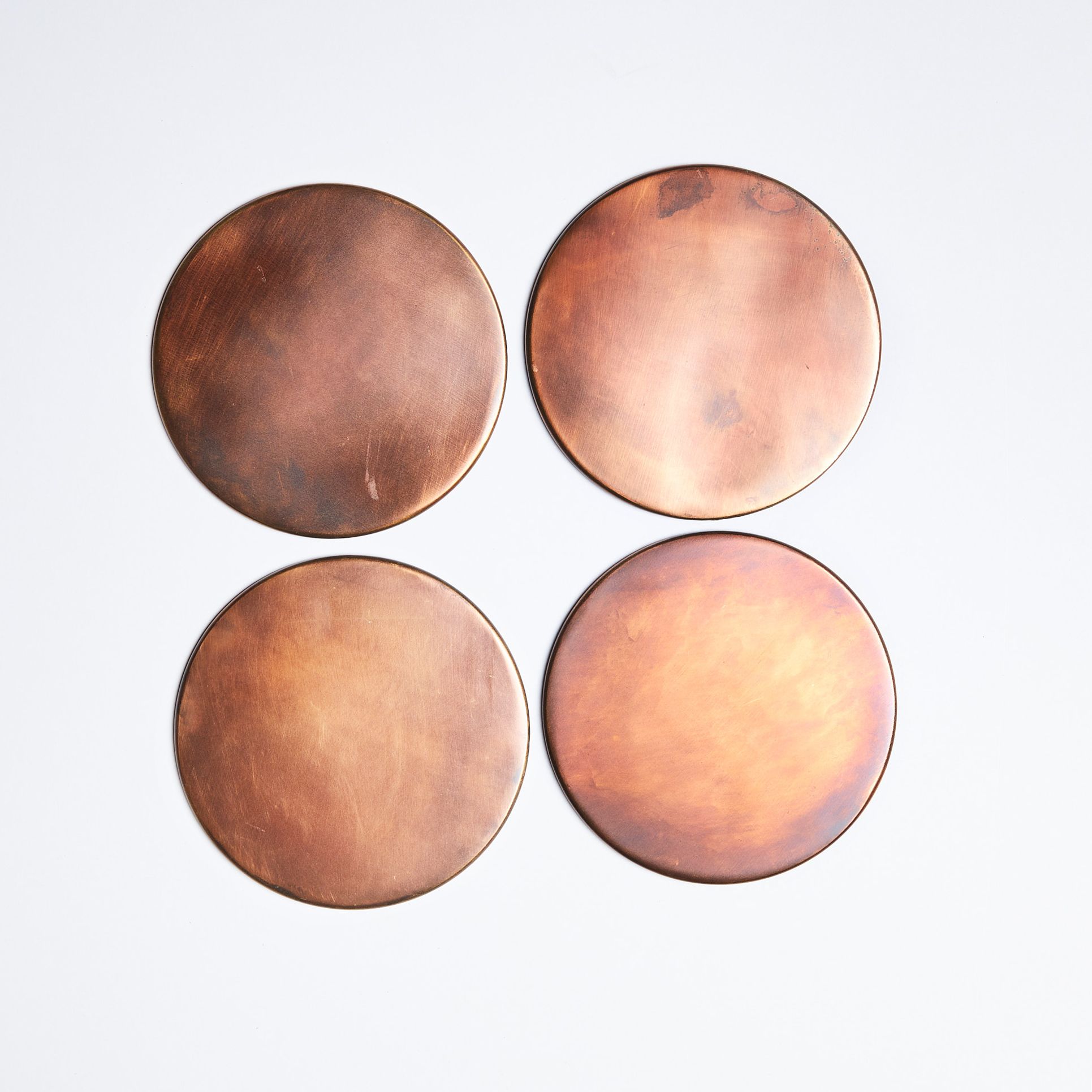 Four round copper coasts arranged in a square grid