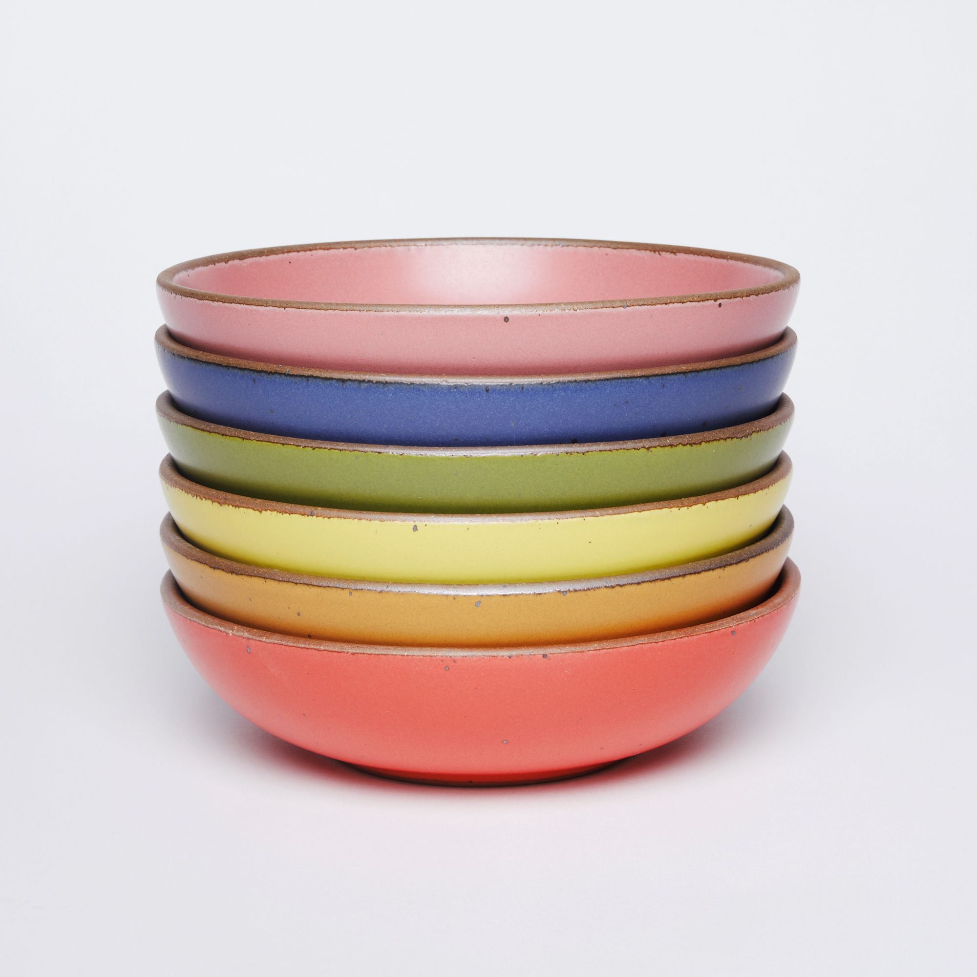 A stack of shallow ceramic bowls, each in a color of the rainbow.