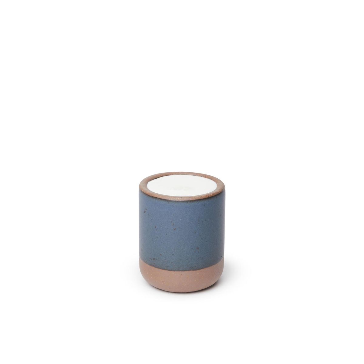 A small, short ceramic mug cup in a toned-down navy color featuring iron speckles and unglazed rim and bottom base, filled with milk.