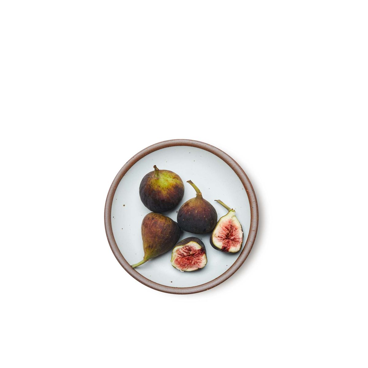 Figs placed on a dessert sized ceramic plate in a cool white color featuring iron speckles and an unglazed rim.