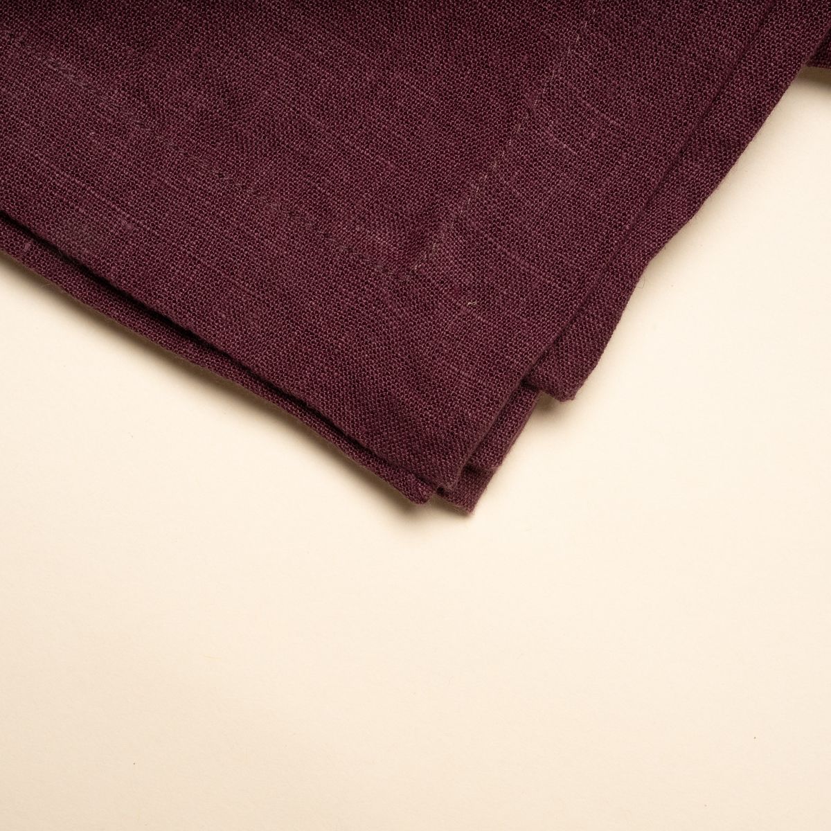 A closeup of a folded linen tablecloth in a deep purple color