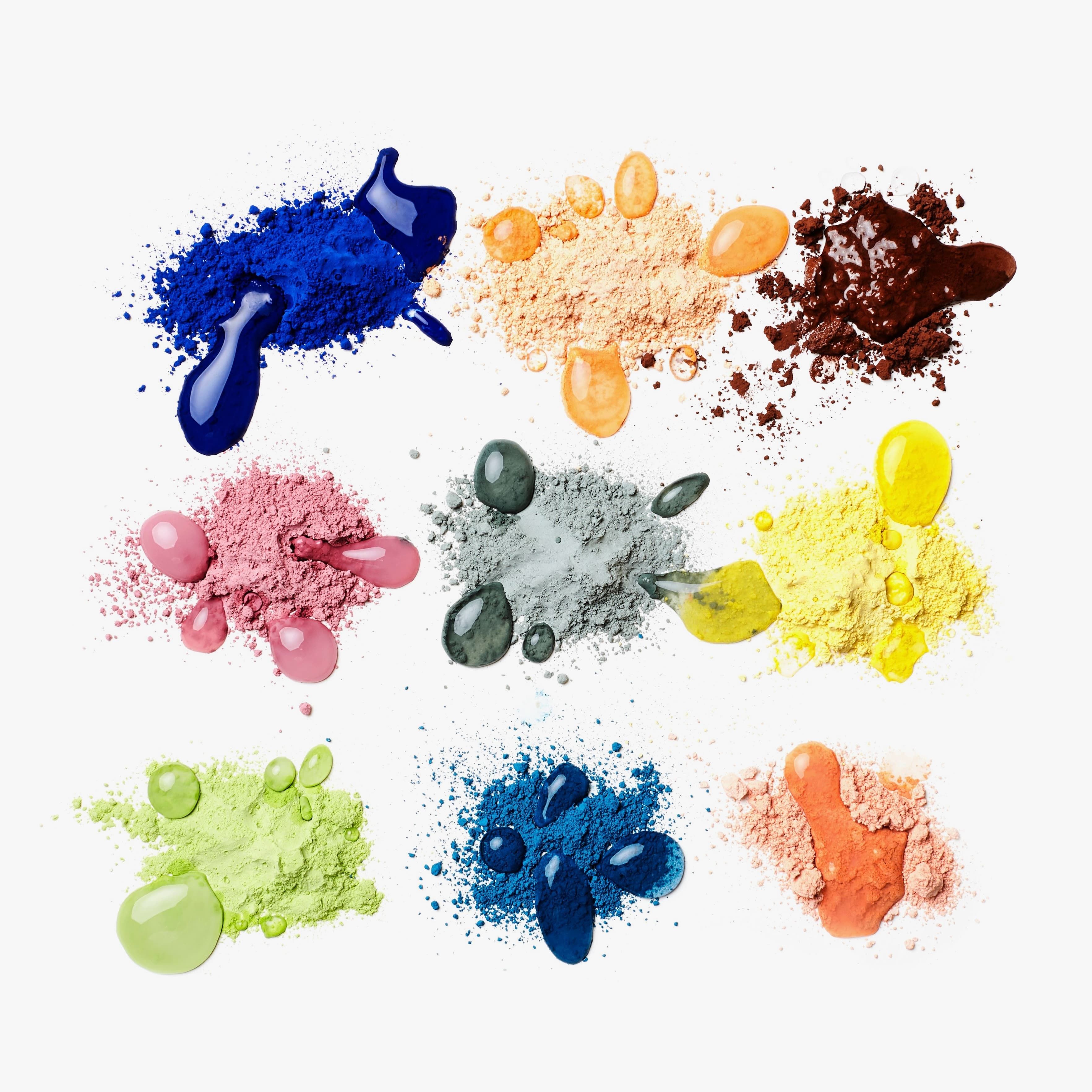 9 different powders in a rainbow of colors with little droplets of water on each.