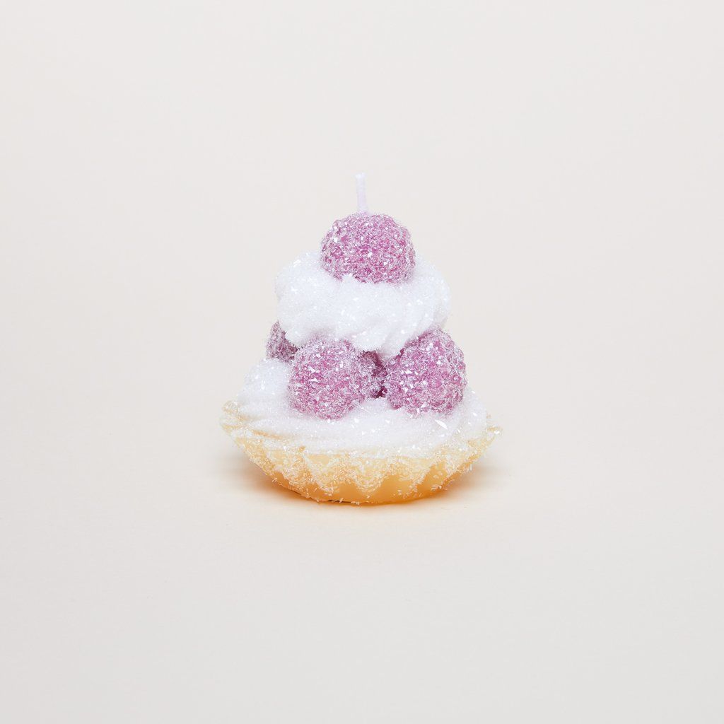 A candle that is made to look, in size, shape and color, like a pastry shell with icing and sugar-sprinkled raspberries.